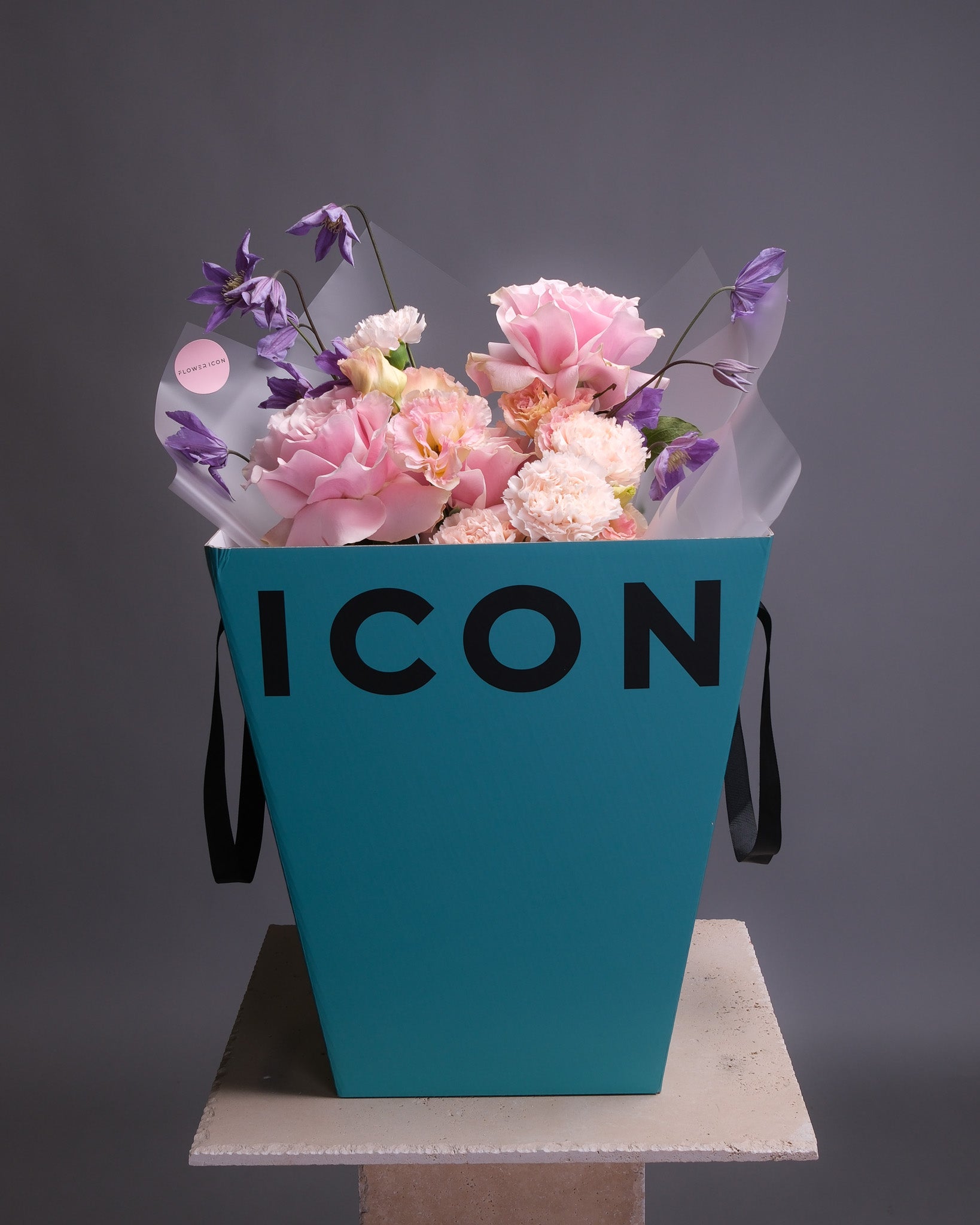 Lush floral arrangement of pink and blush blooms with purple clematis, presented in a signature gift box for a refined, feminine look.