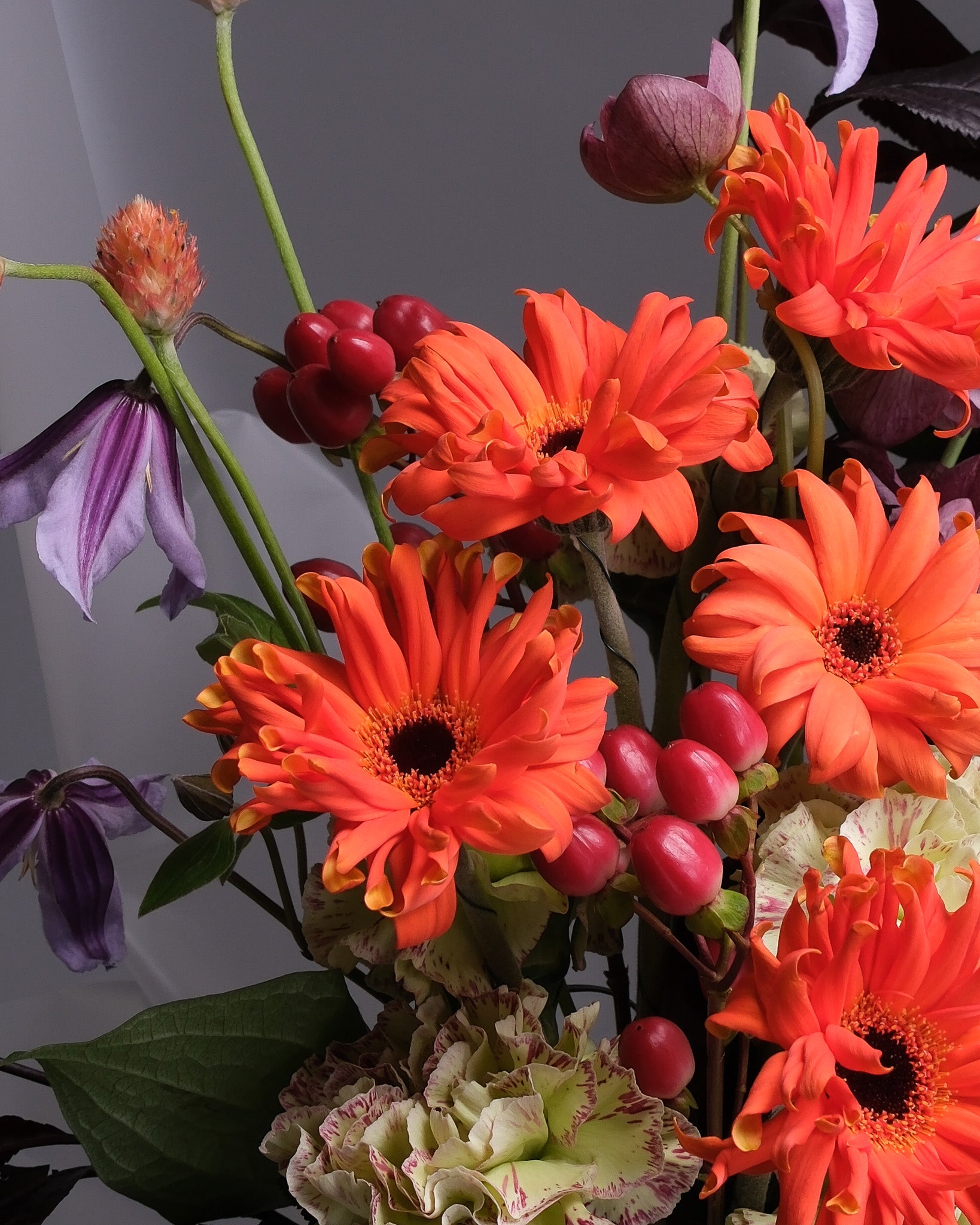 Bouquet of orange flowers with red berries against a dark background