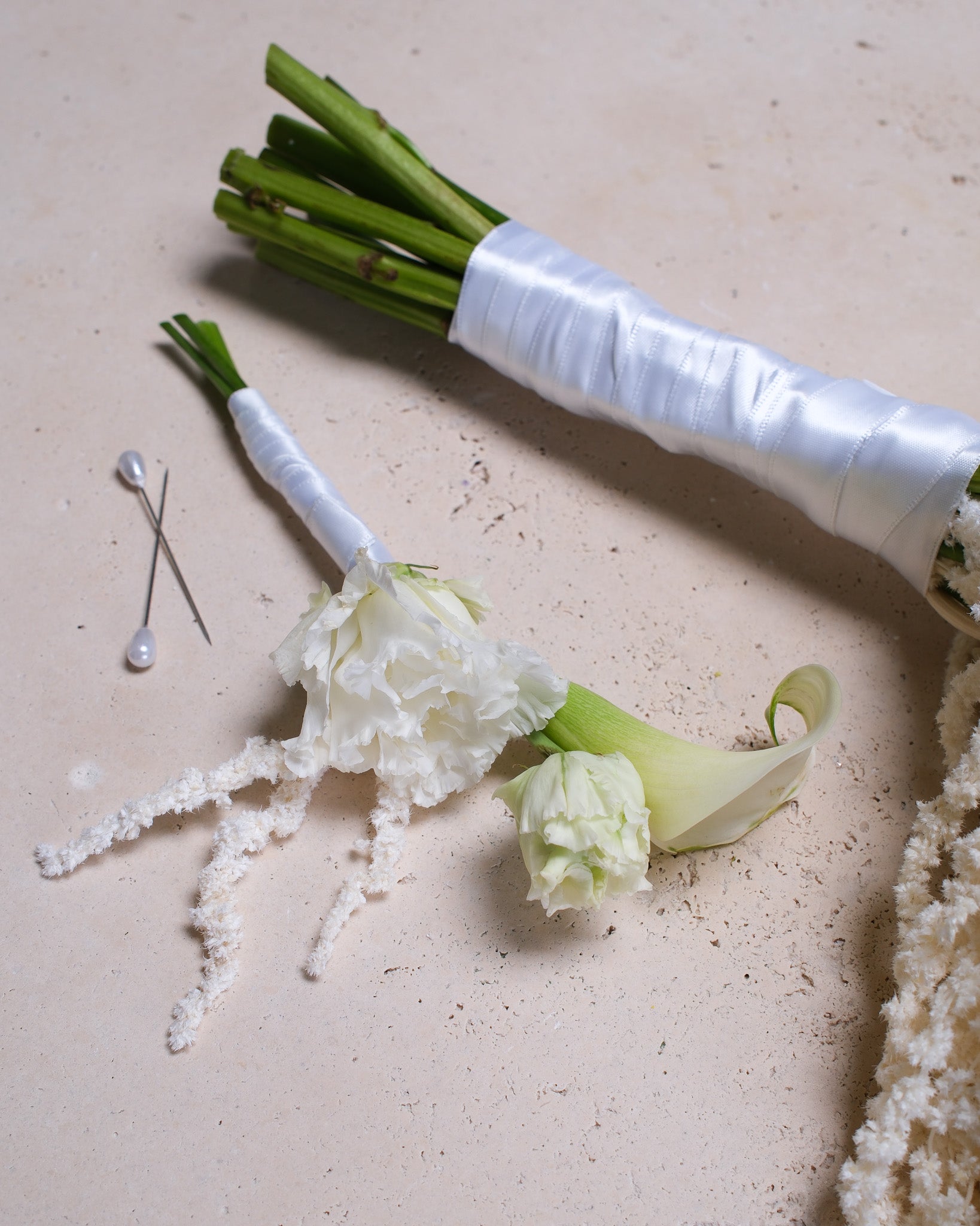 Minimalist white boutonniere with a small white peony bloom and greenery, designed to pair with a modern bridal bouquet.