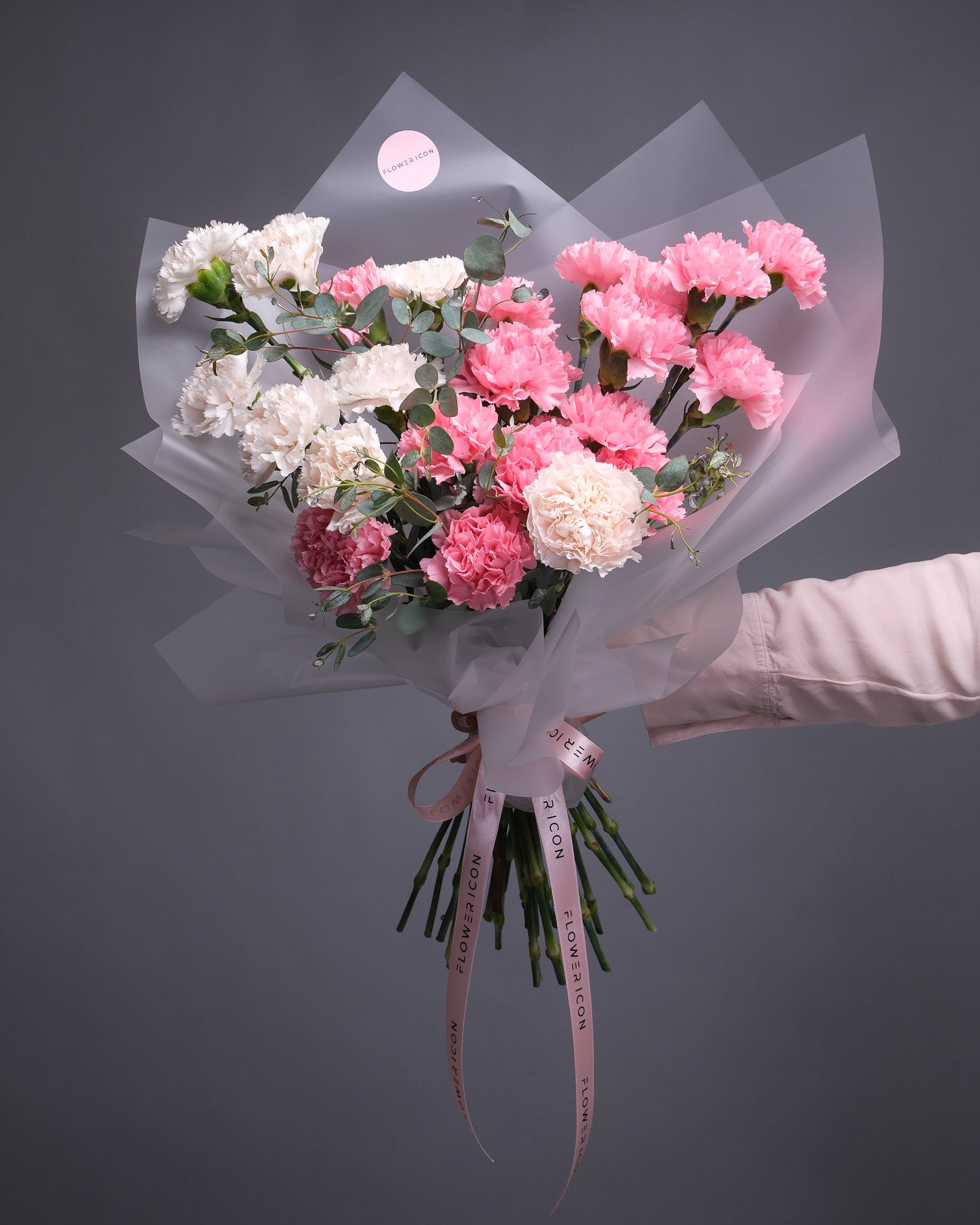Hand-held bouquet with light and dark pink carnations accented by soft greens – romantic and textured design