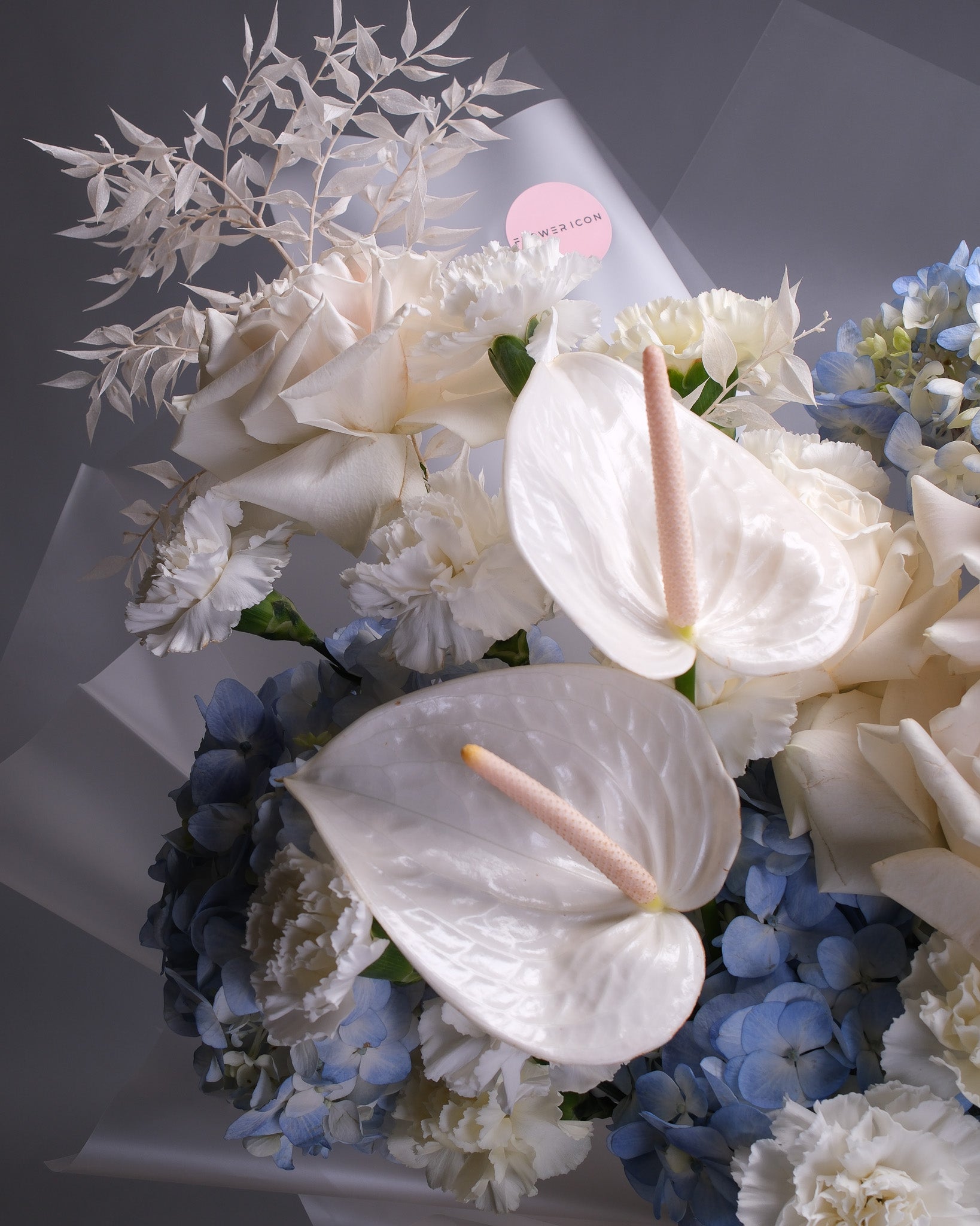 Close up of a bouquet of flowers with white and blue colors on a gray background