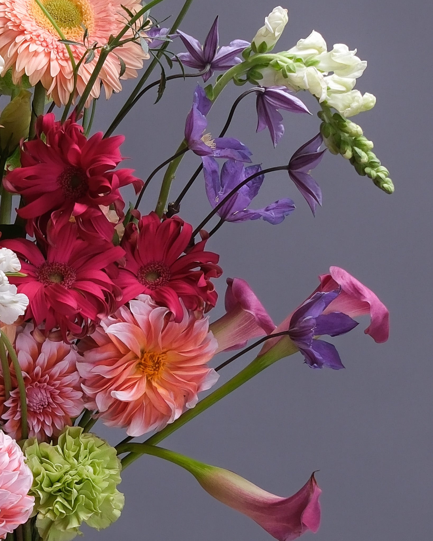 Lush and colorful flower arrangement with a variety of seasonal blooms in bright pink, orange, yellow, and purple tones, perfect for summer celebrations.