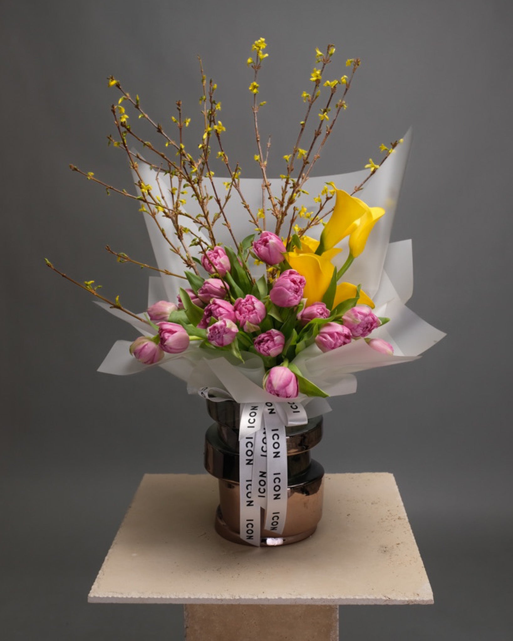 Modern bouquet with purple tulips, yellow calla lilies, and forsythia branches in a vase – bright and artistic floral design