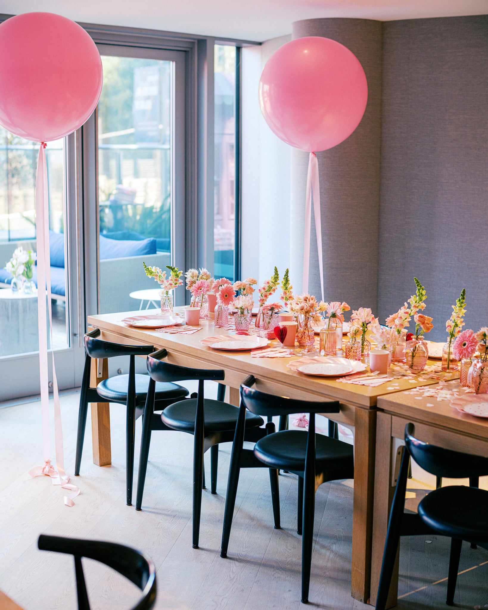 Party table setup with small vases of seasonal pink flowers in various shades – elegant and festive floral styling