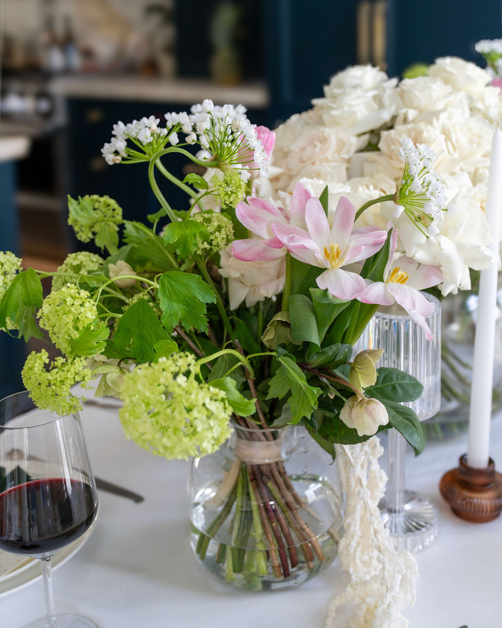 Mixed floral arrangement of white roses and assorted greens, designed with a luxurious and timeless feel.