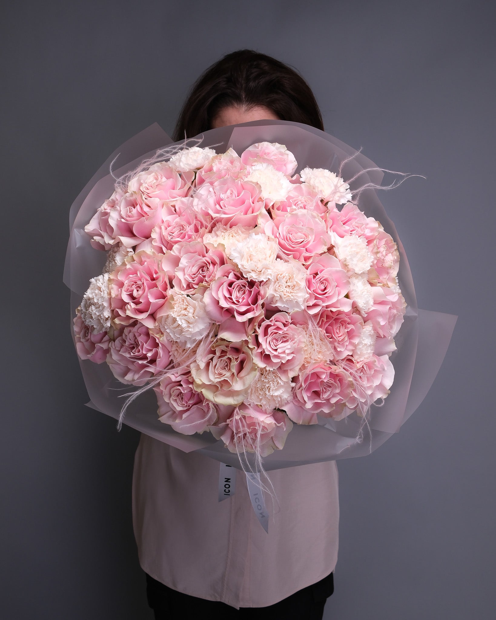 Large luxurious bouquet featuring extra-large pink roses, soft blush carnations, and wispy stipa grass, arranged in an elegant, romantic style.