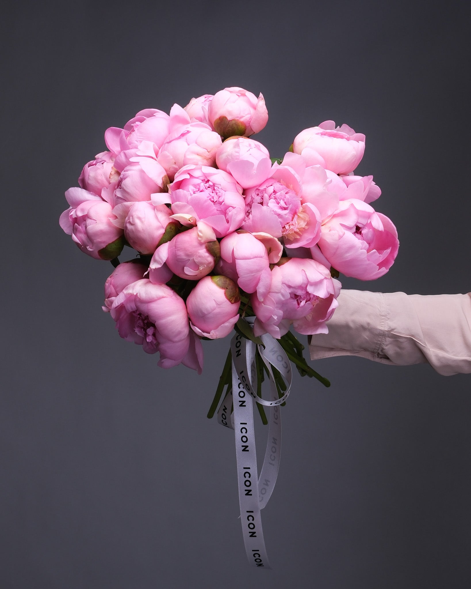 Handheld mono bouquet of lush peonies in full bloom, showcasing soft, layered petals.