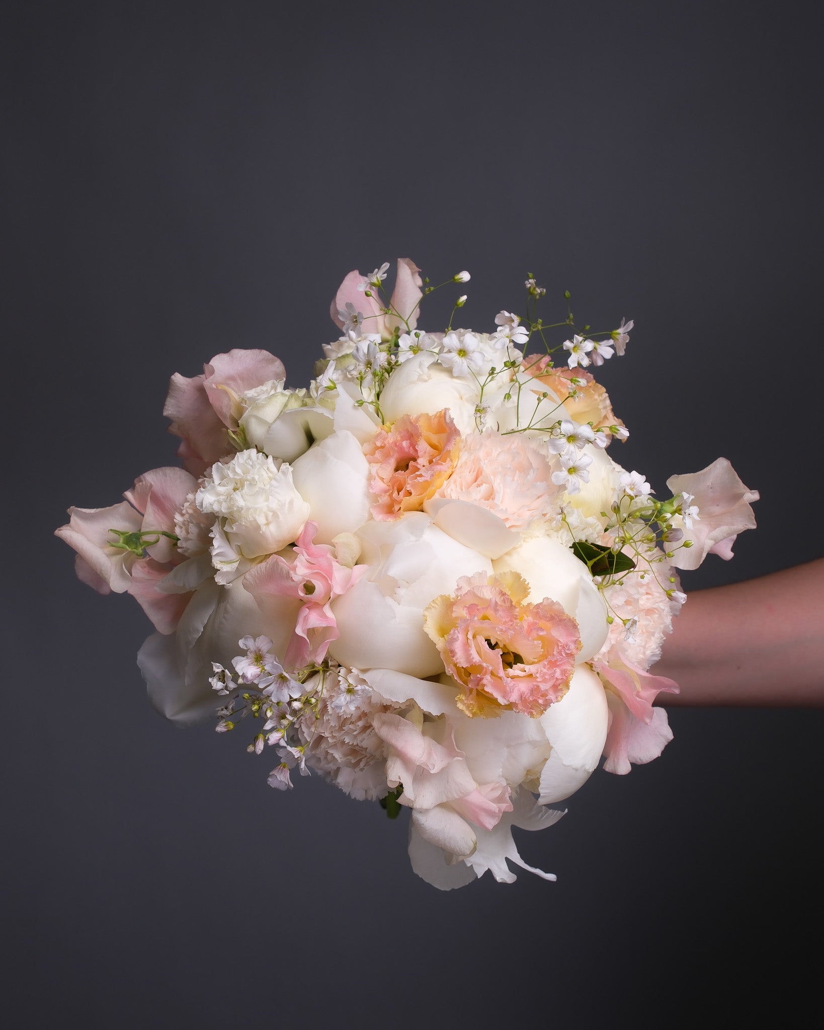 Classical round bouquet in soft blush tones, featuring sweet peas, white peonies, and lisianthus for a delicate, romantic, and gently textured look.