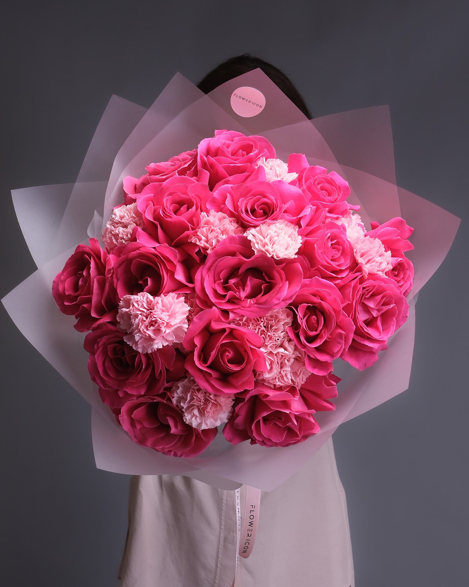 Bouquet of pink roses and carnations held by a person against a dark background
