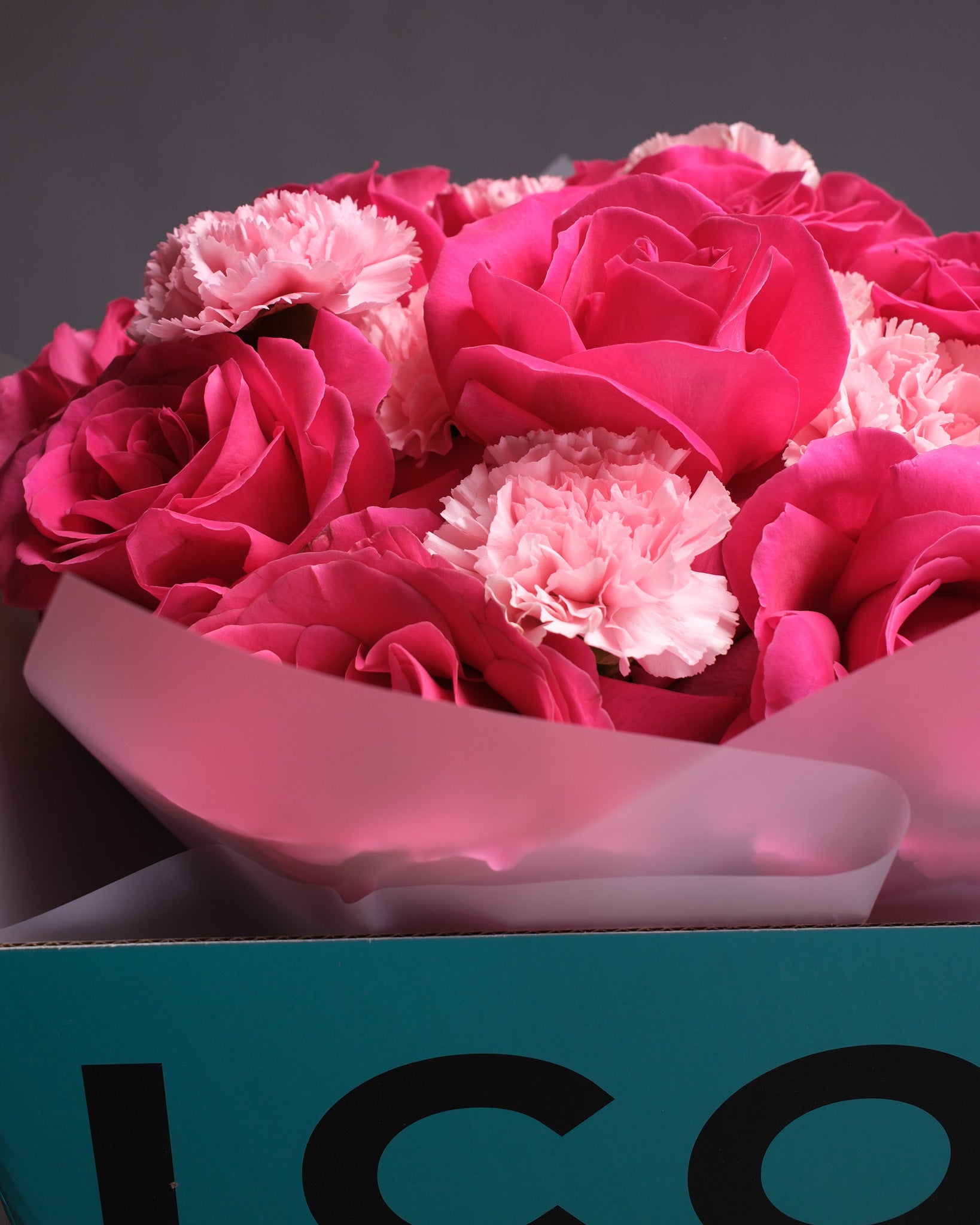 Bouquet of pink roses and carnations in a box with 'ICON' branding.