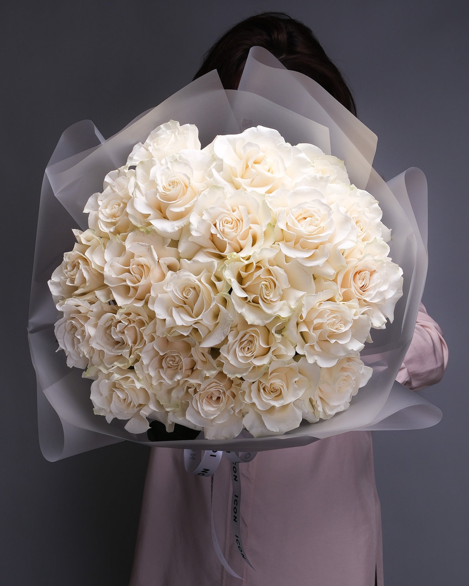 Pure white rose bouquet with fresh green stems, held in hand – timeless floral design for any occasion