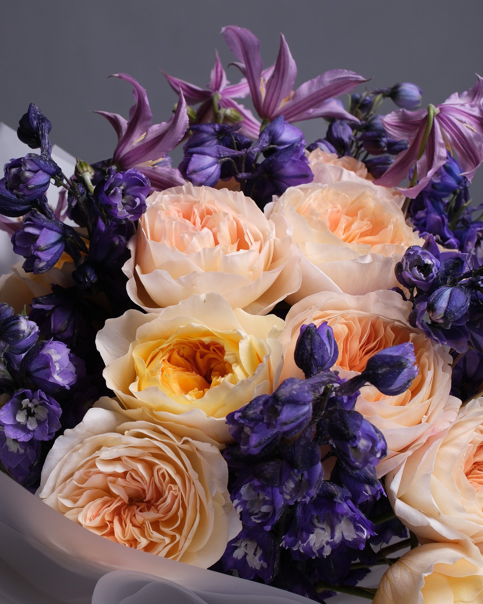 A close up of garden roses, clematis and delphinium