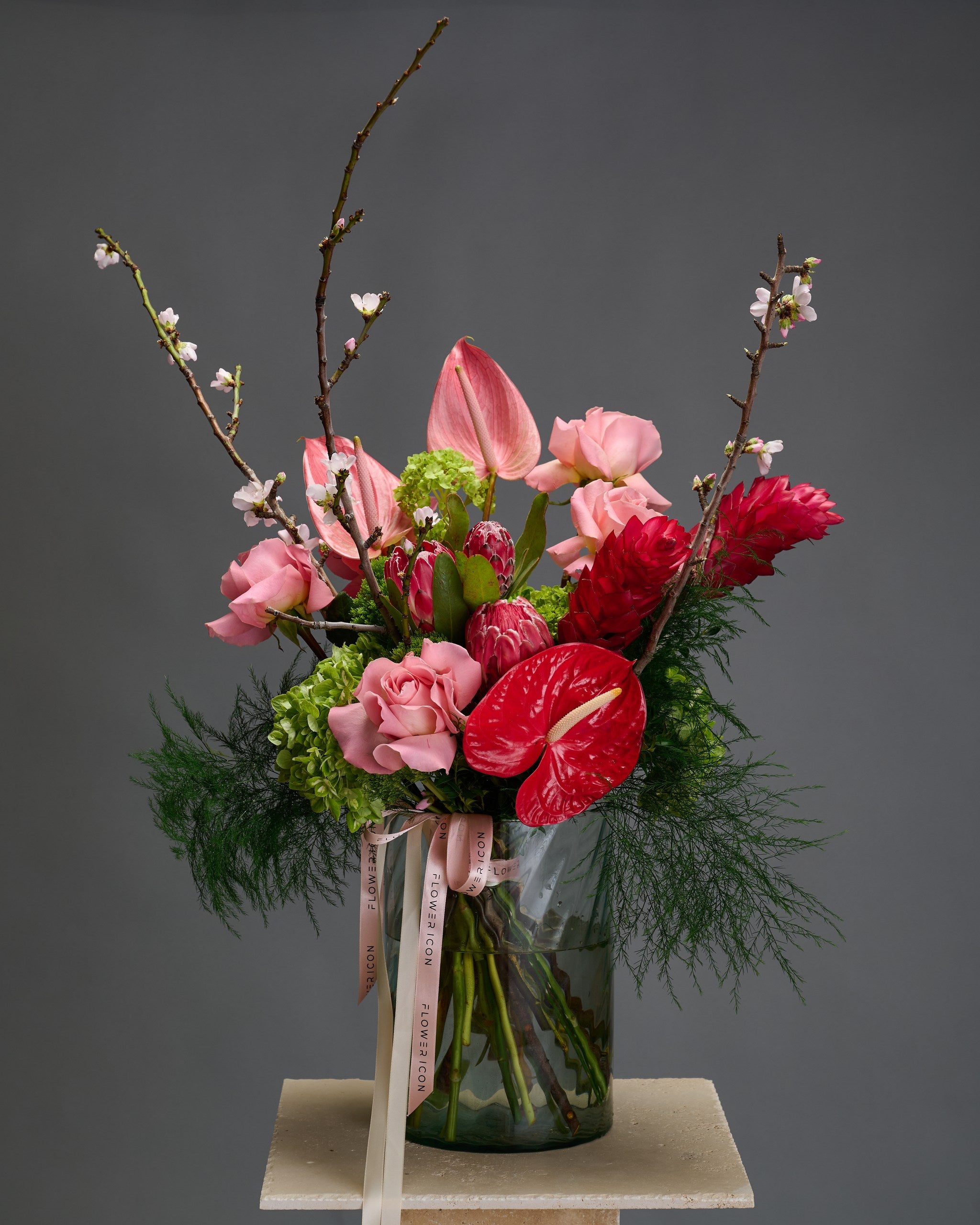 Lush pink and red tropical bouquet with viburnum, proteas, and roses styled in a modern vase – The Blooming Gatsby