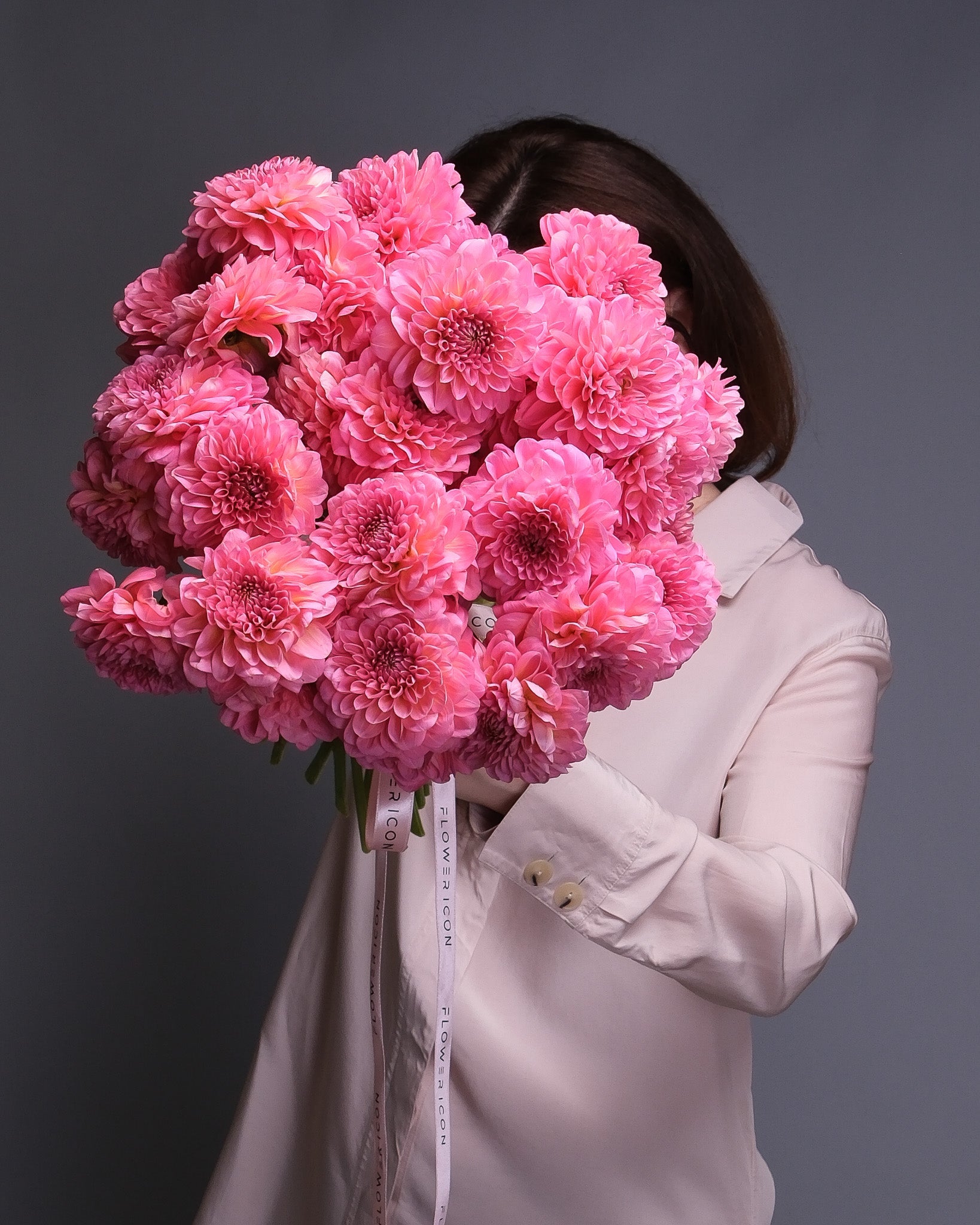 Handheld dahlia bouquet featuring vibrant pink and orange dahlias with seasonal accents, perfect for summer gifting.