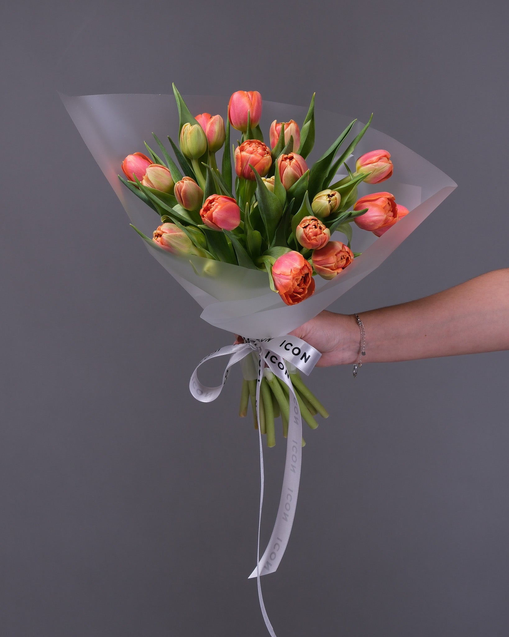 Bouquet of tulips held by a hand against a gray background