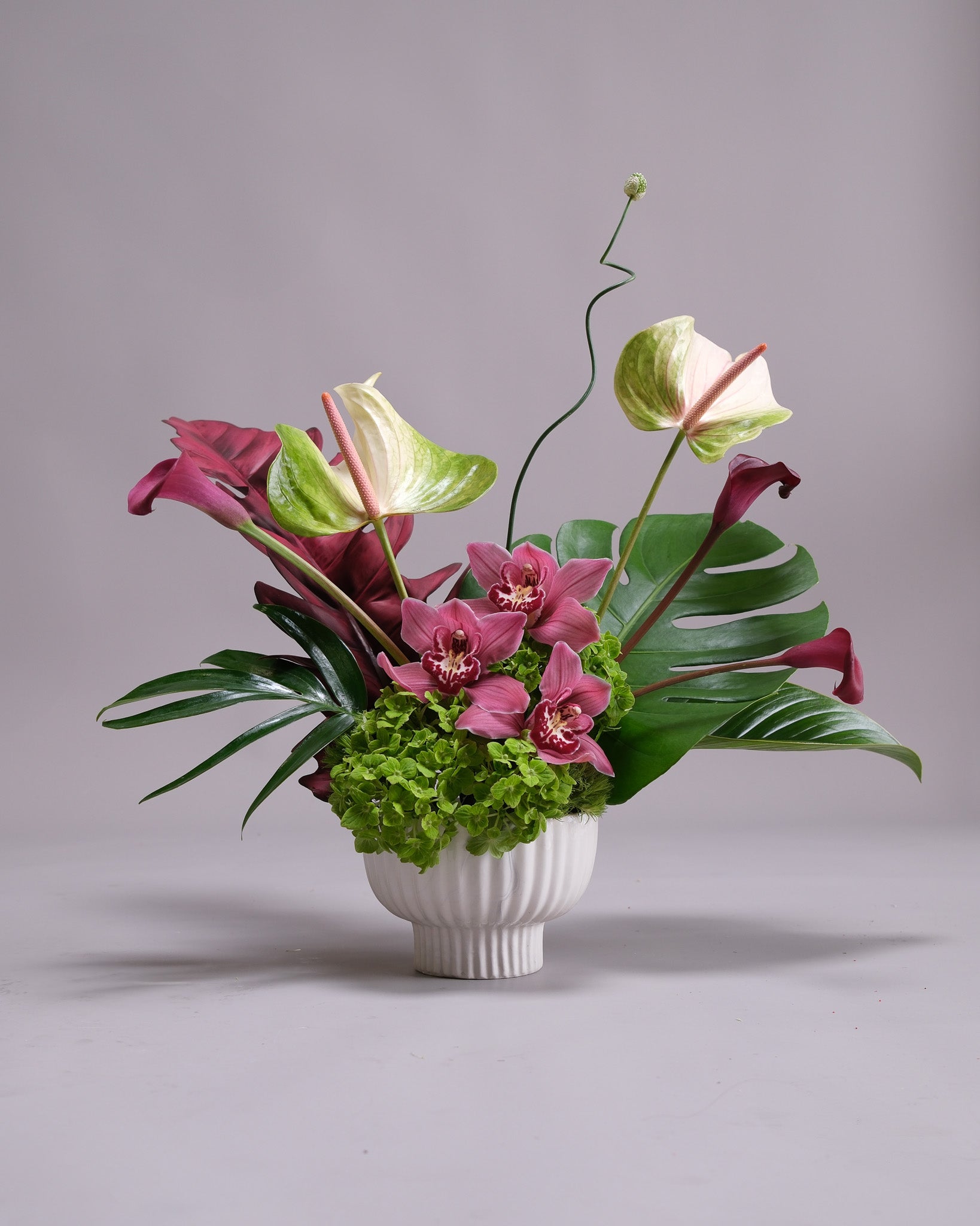 Floral arrangement with pink and green flowers in a white vase on a gray background
