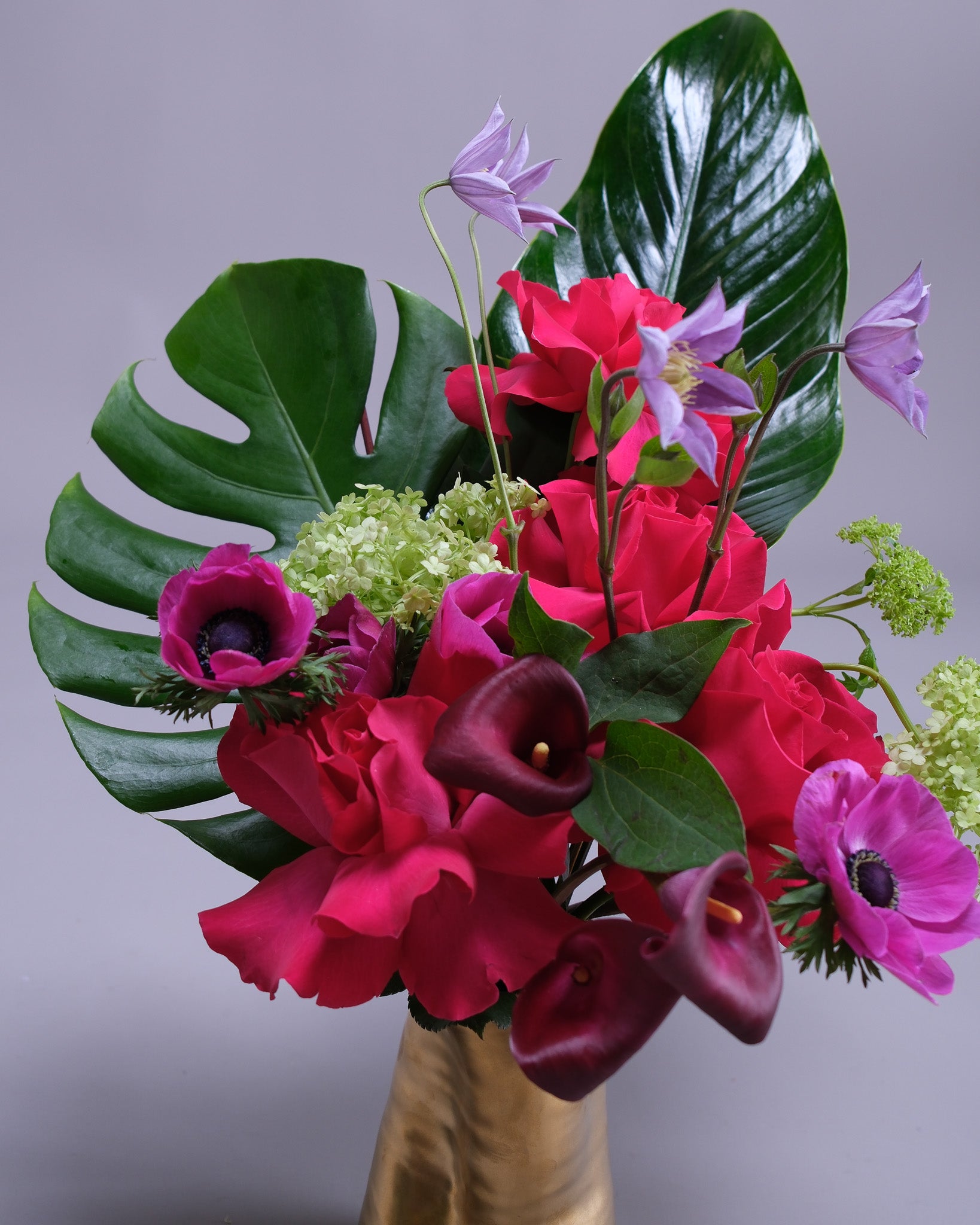 Bouquet of flowers with red and purple flowers in a vase against a gray background