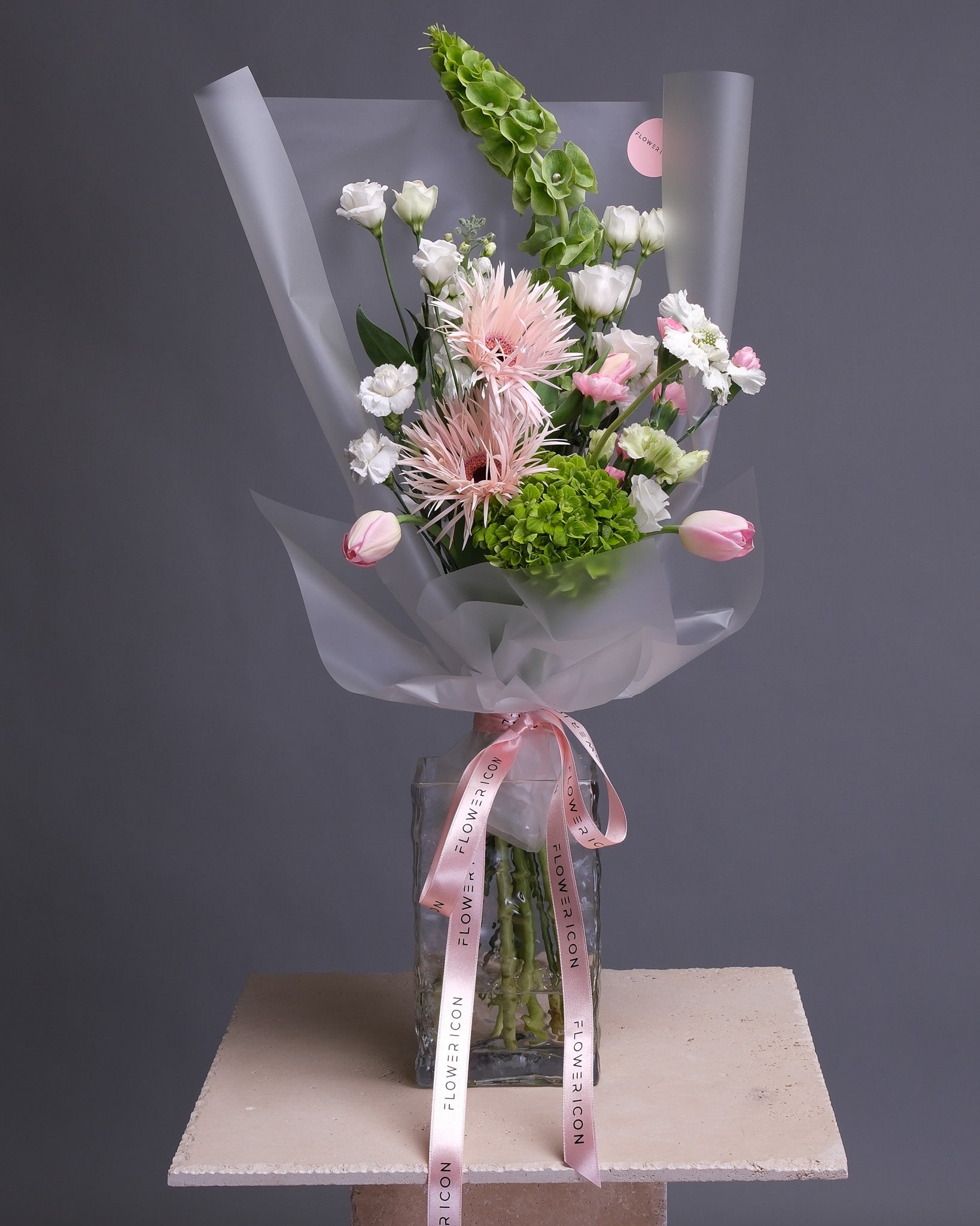 Florist’s choice designer bouquet featuring tulips, gerbera daisies, and assorted greens, artfully arranged in a vase with a fresh, modern style.
