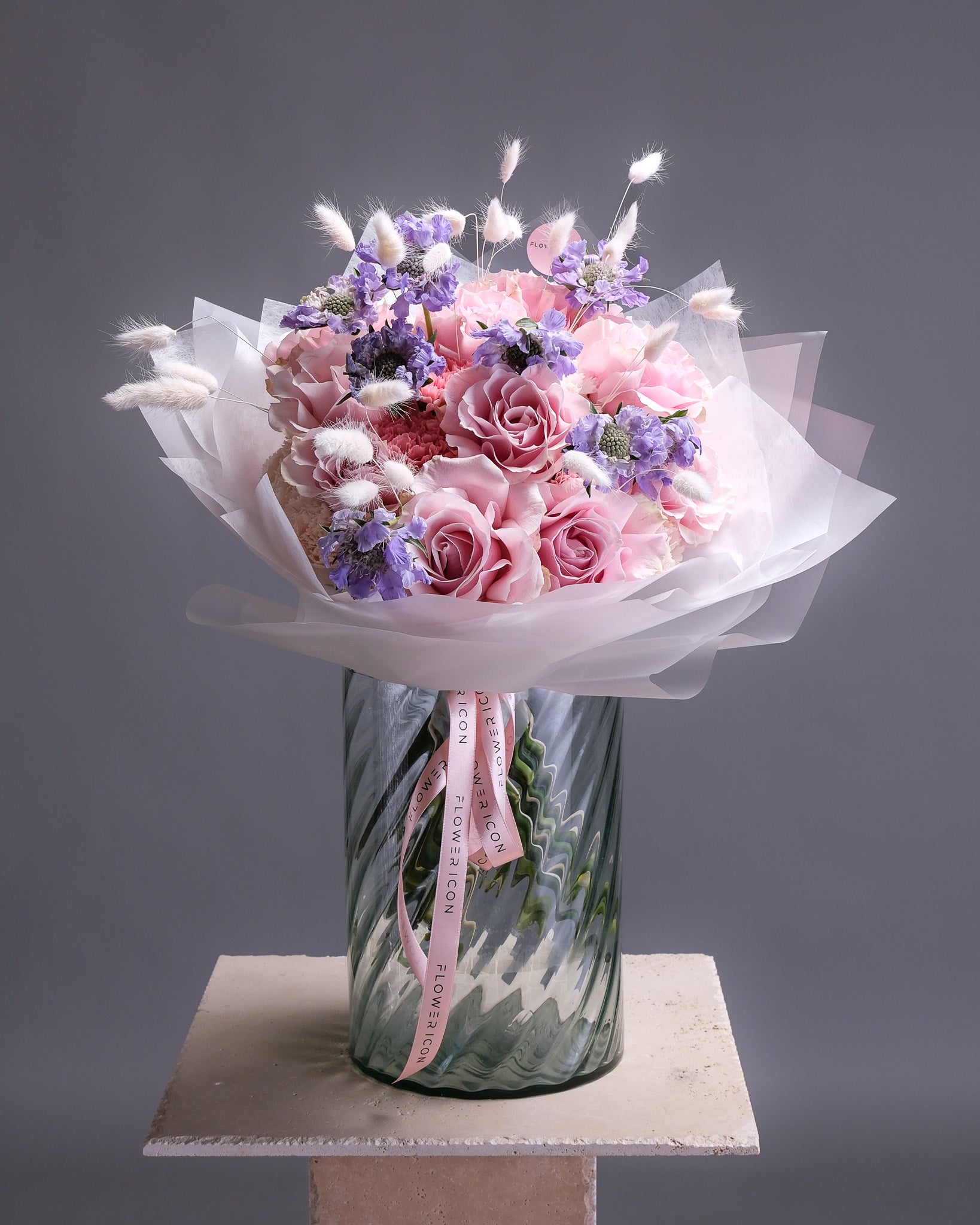 Bouquet of pink and purple flowers in a clear vase on a gray background
