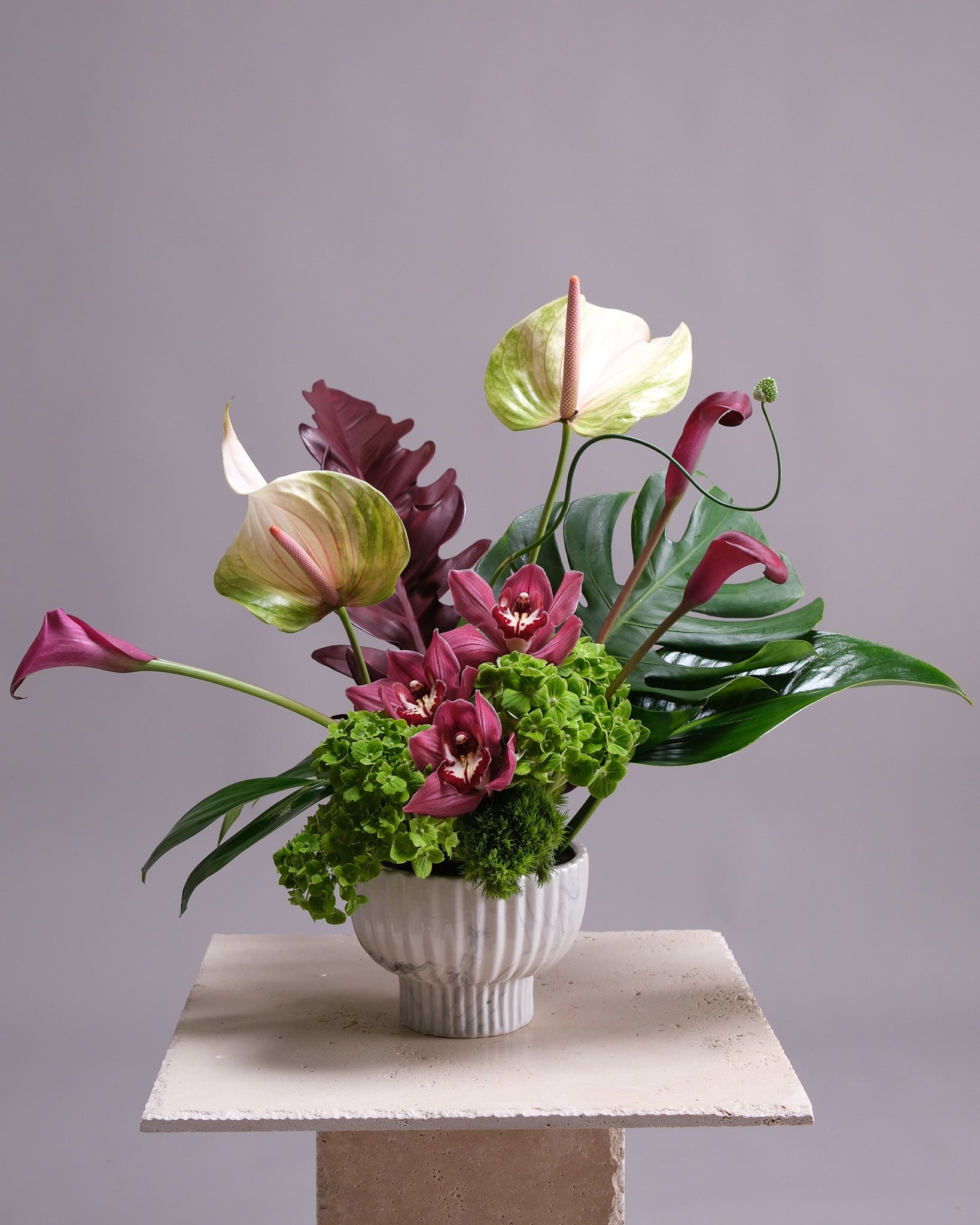 Floral arrangement with pink and green flowers in a white vase on a gray background