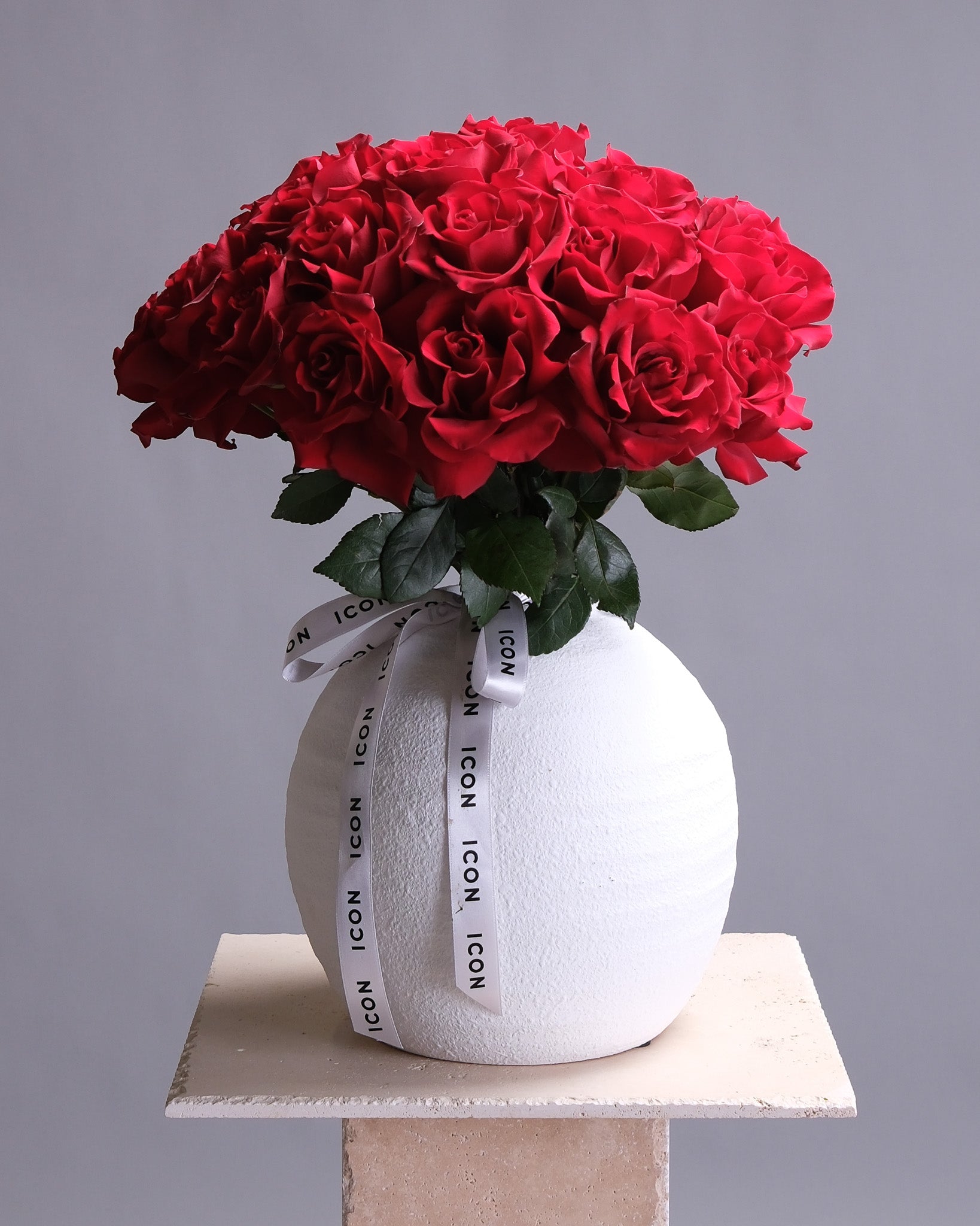 White vase with red roses on a gray background