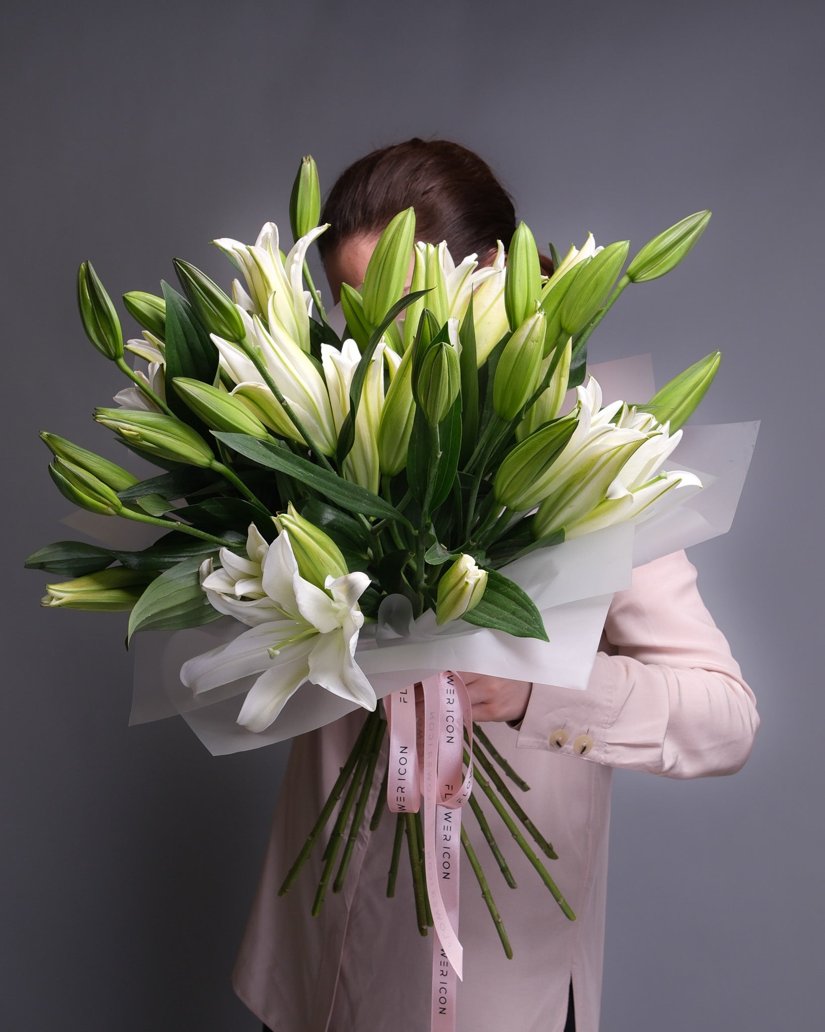 Large mono bouquet of white lilies with long stems and open blooms, arranged in an elegant and sculptural style.