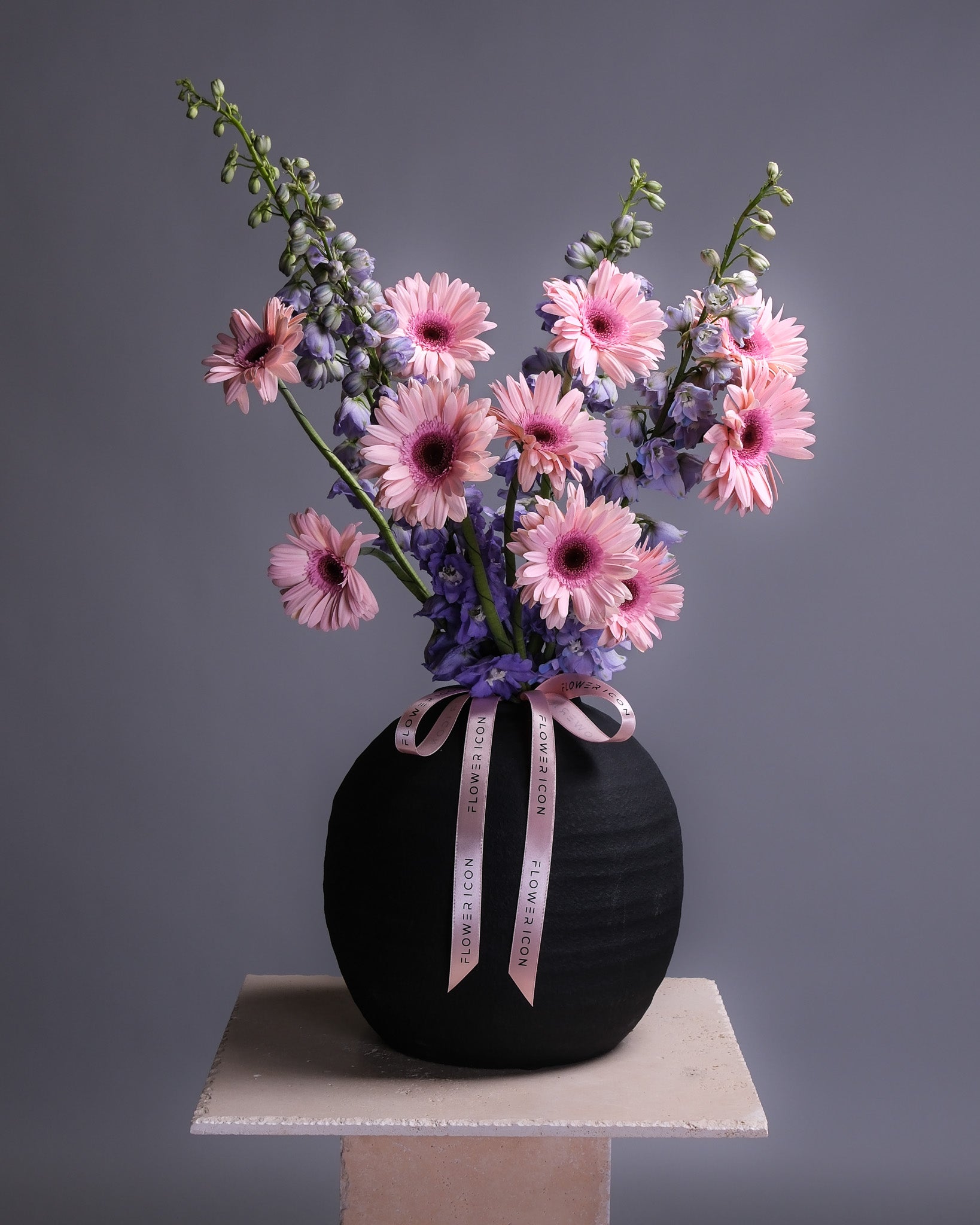Black vase with pink Gerberas and Purple delphinium 