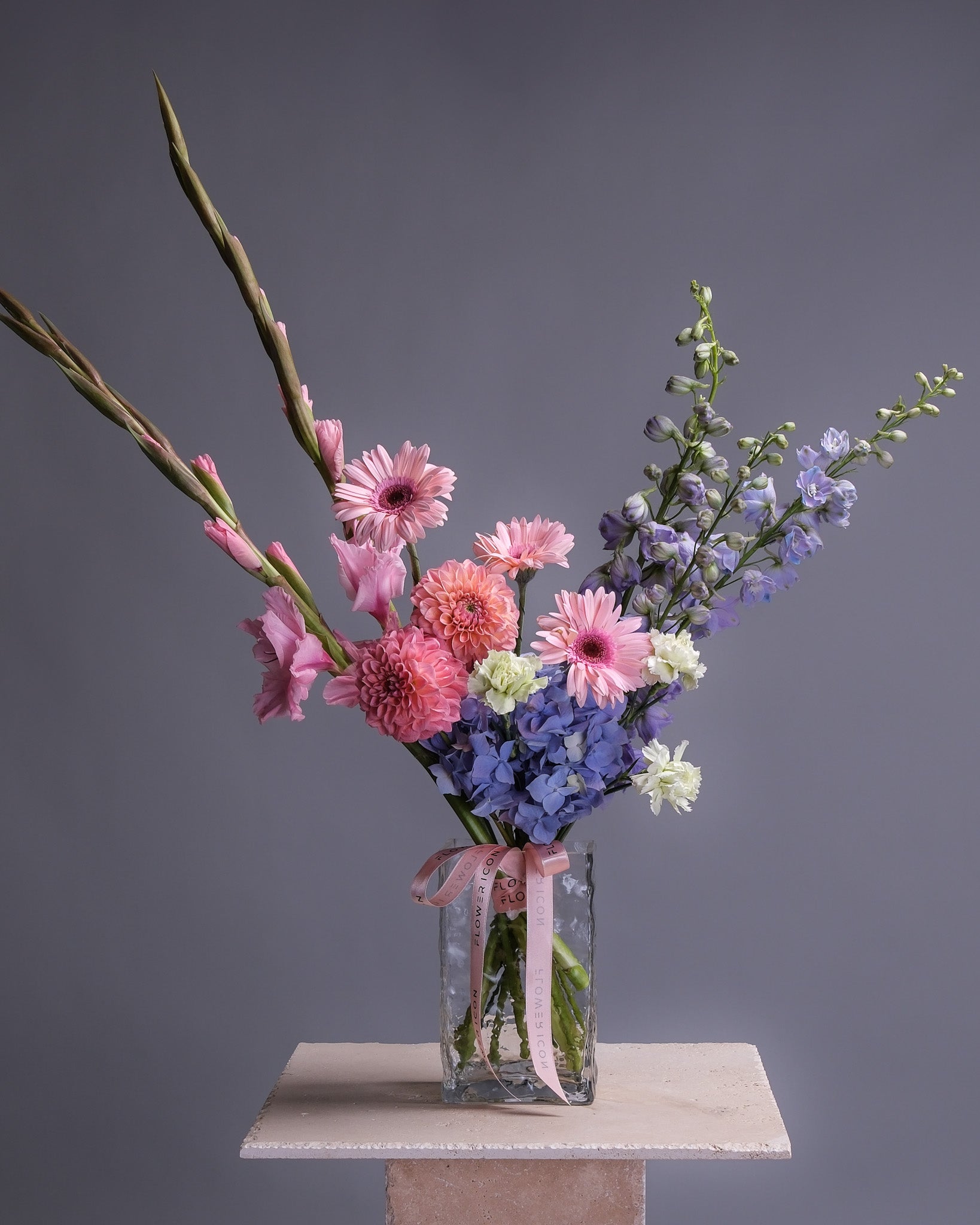 Vase of flowers with a pink ribbon on a gray background