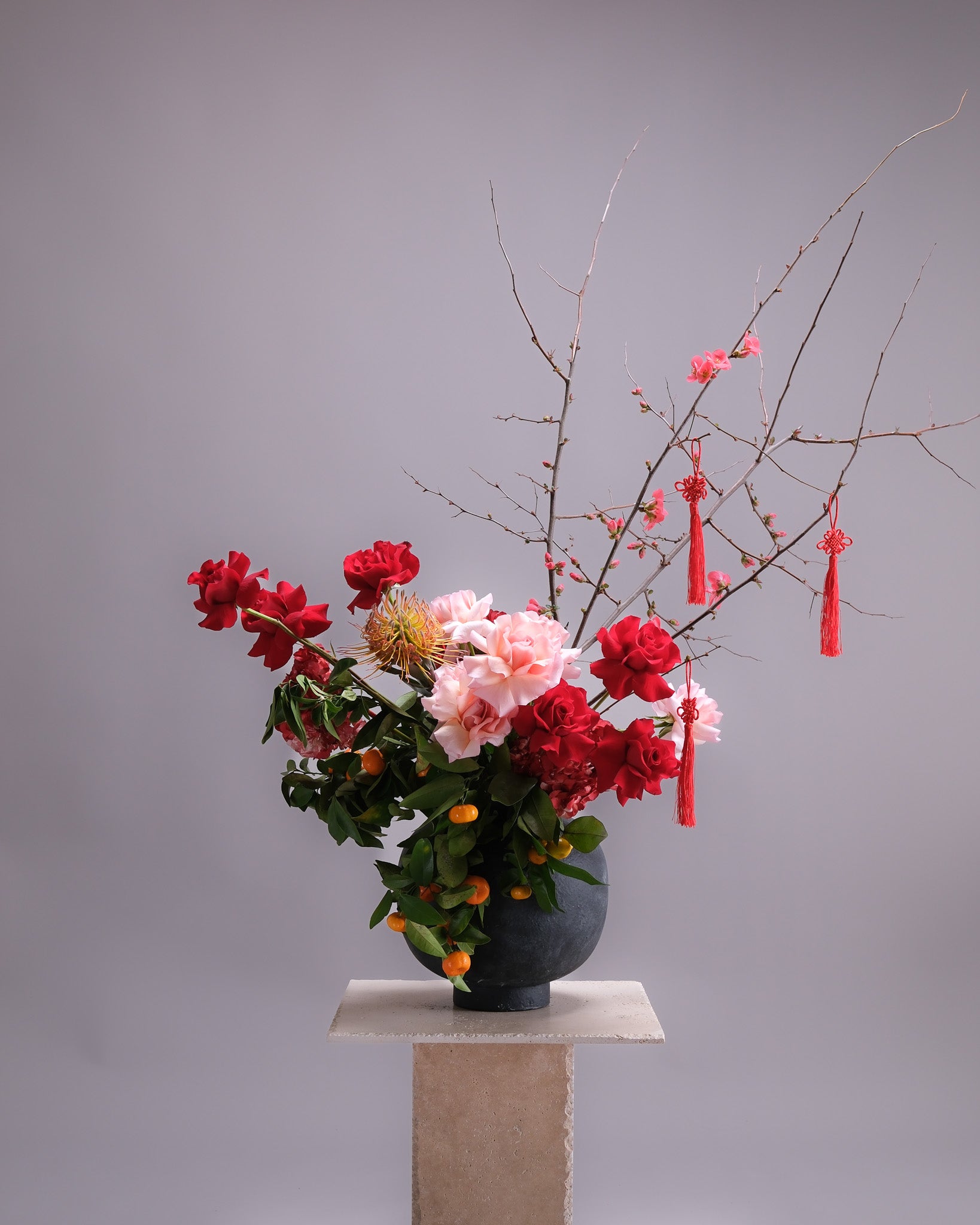 Floral arrangement with red and pink flowers in a vase on a gray background