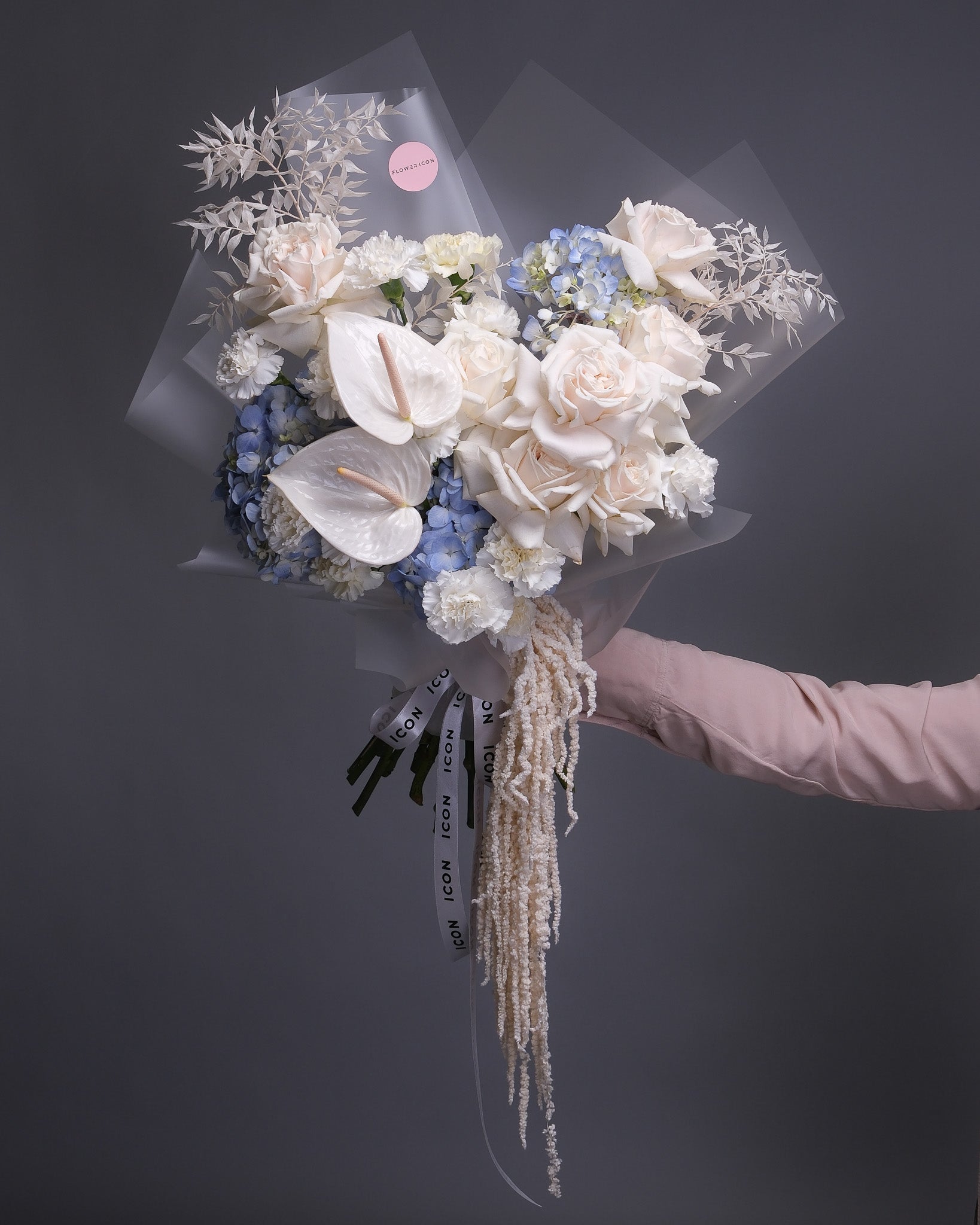 Bouquet of white and blue flowers held by a person against a dark background