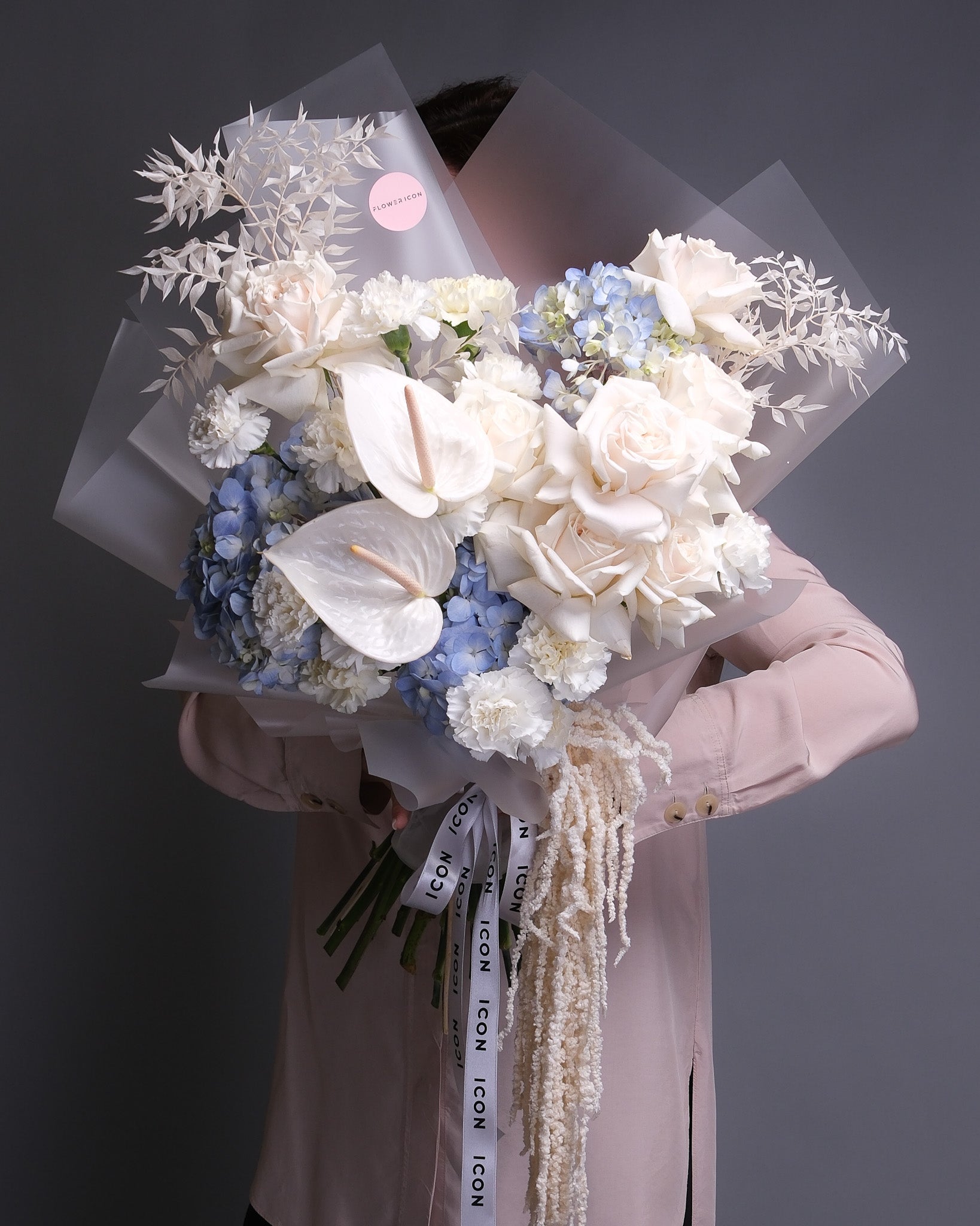 Pearl anthuriums, premium white roses, blue hydrangeas, carnations, amaranth hand-held bouquet. 