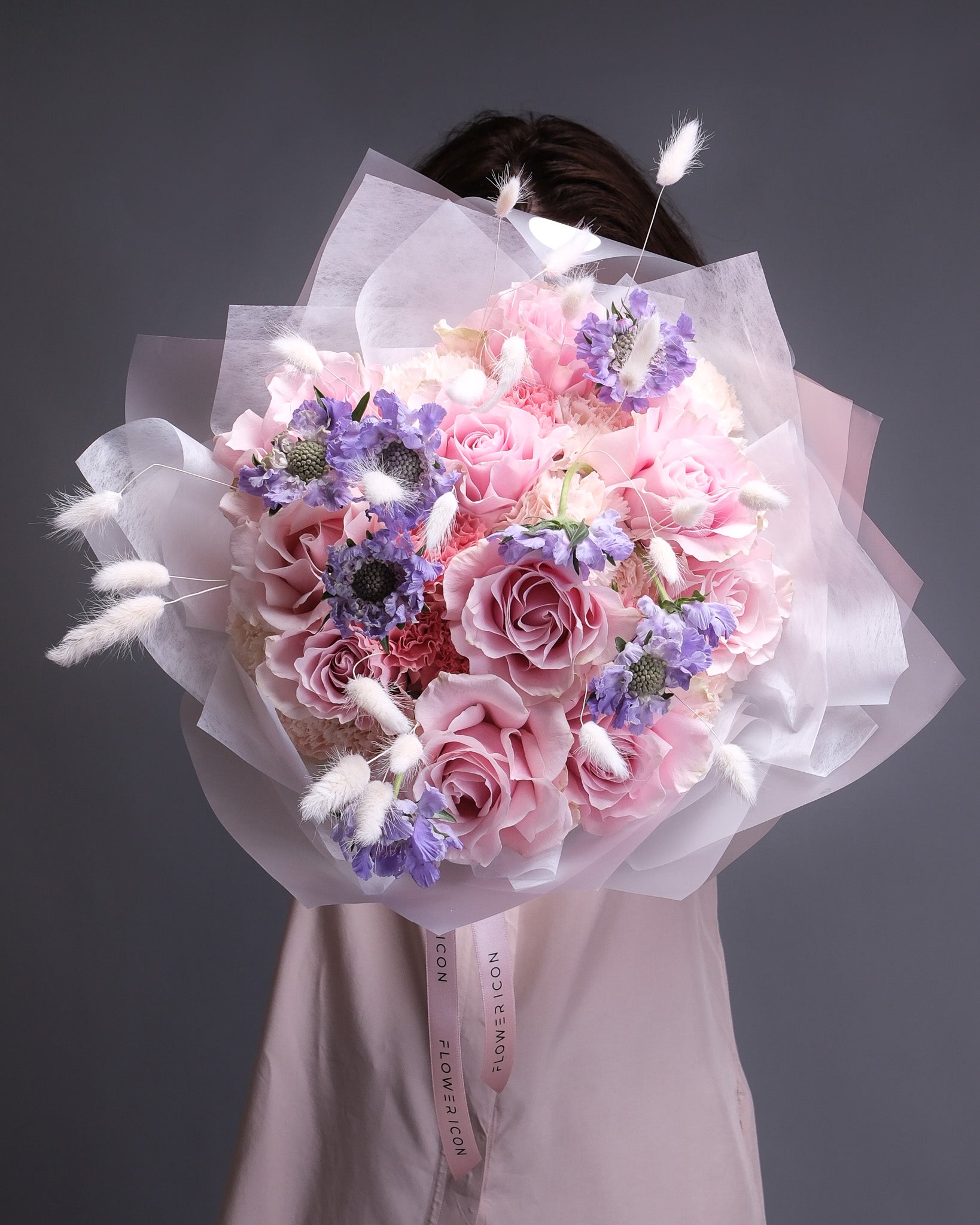 Bouquet of pink and purple flowers with white decorative elements on a dark background