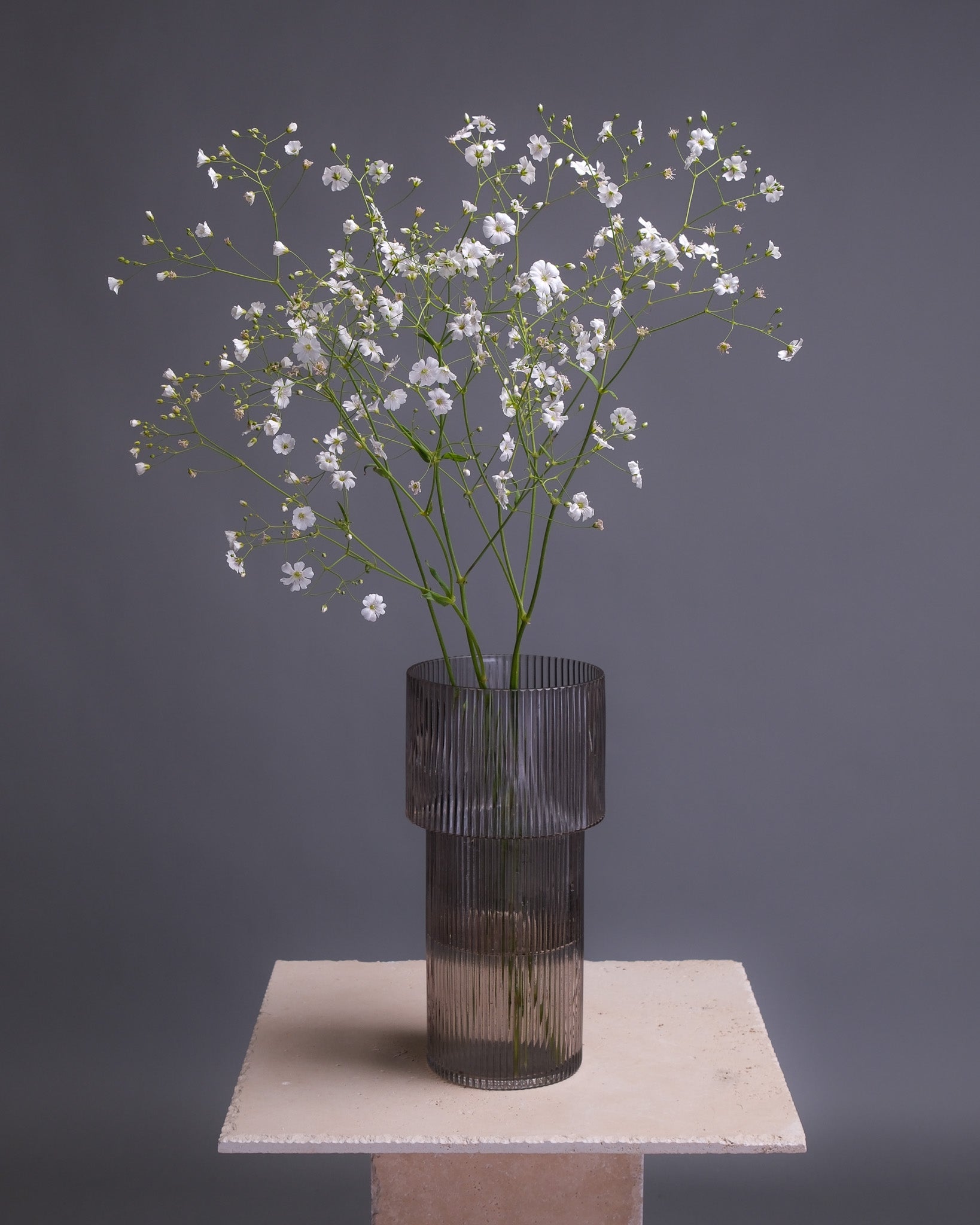 Long glass vase with vertical striped texture, offering a modern, elegant look ideal for contemporary floral arrangements or minimalist decor.