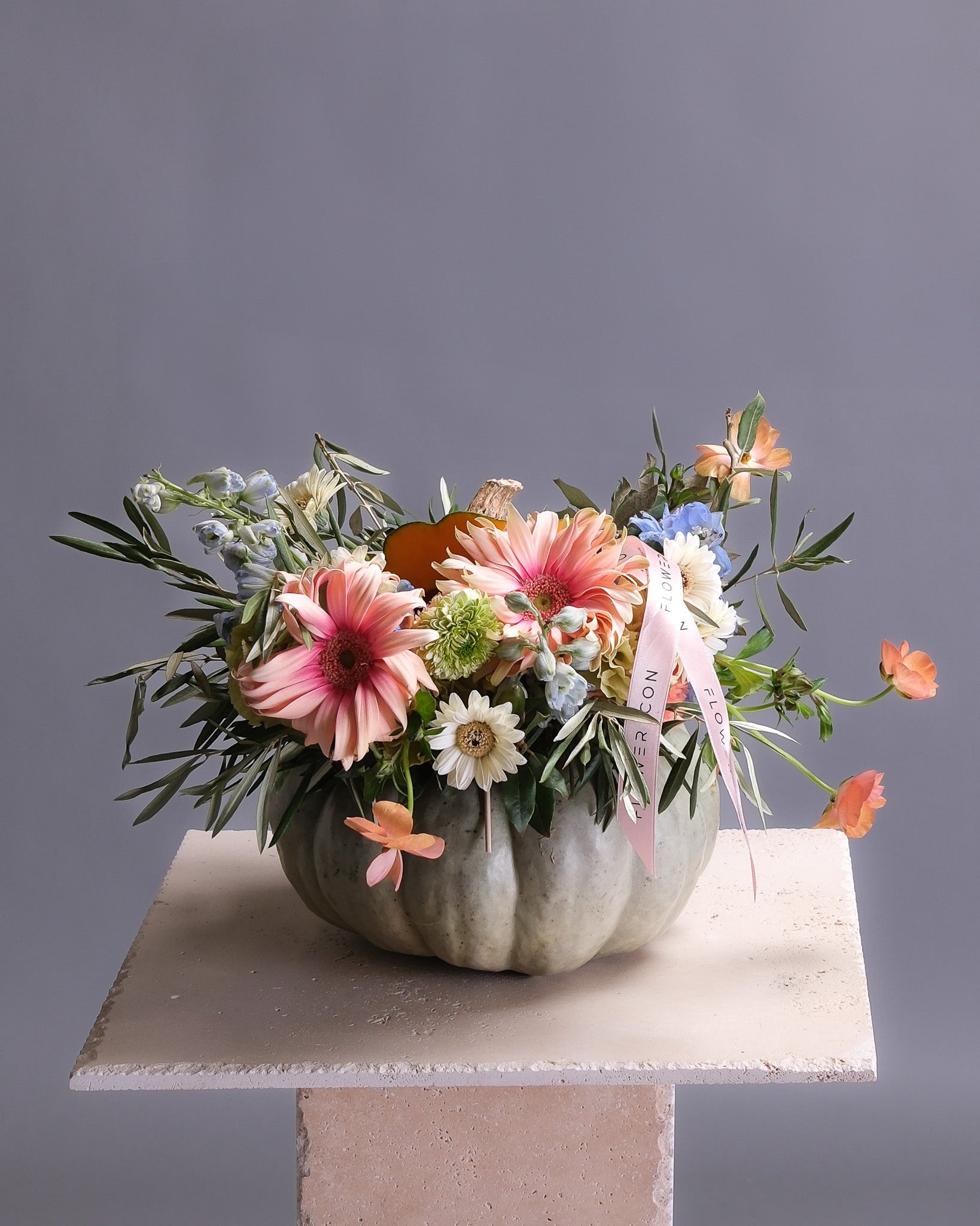 Decorative pumpkin with a floral arrangement on a gray background