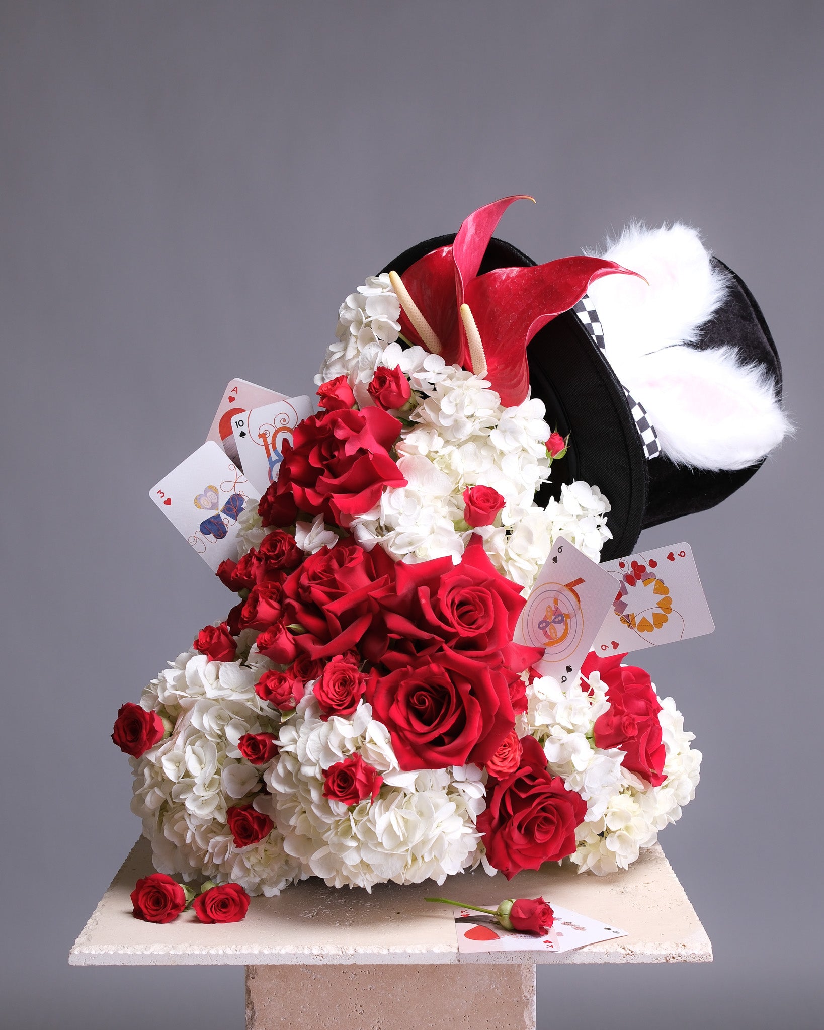Floral arrangement shaped like a hat with red and white flowers on a gray background