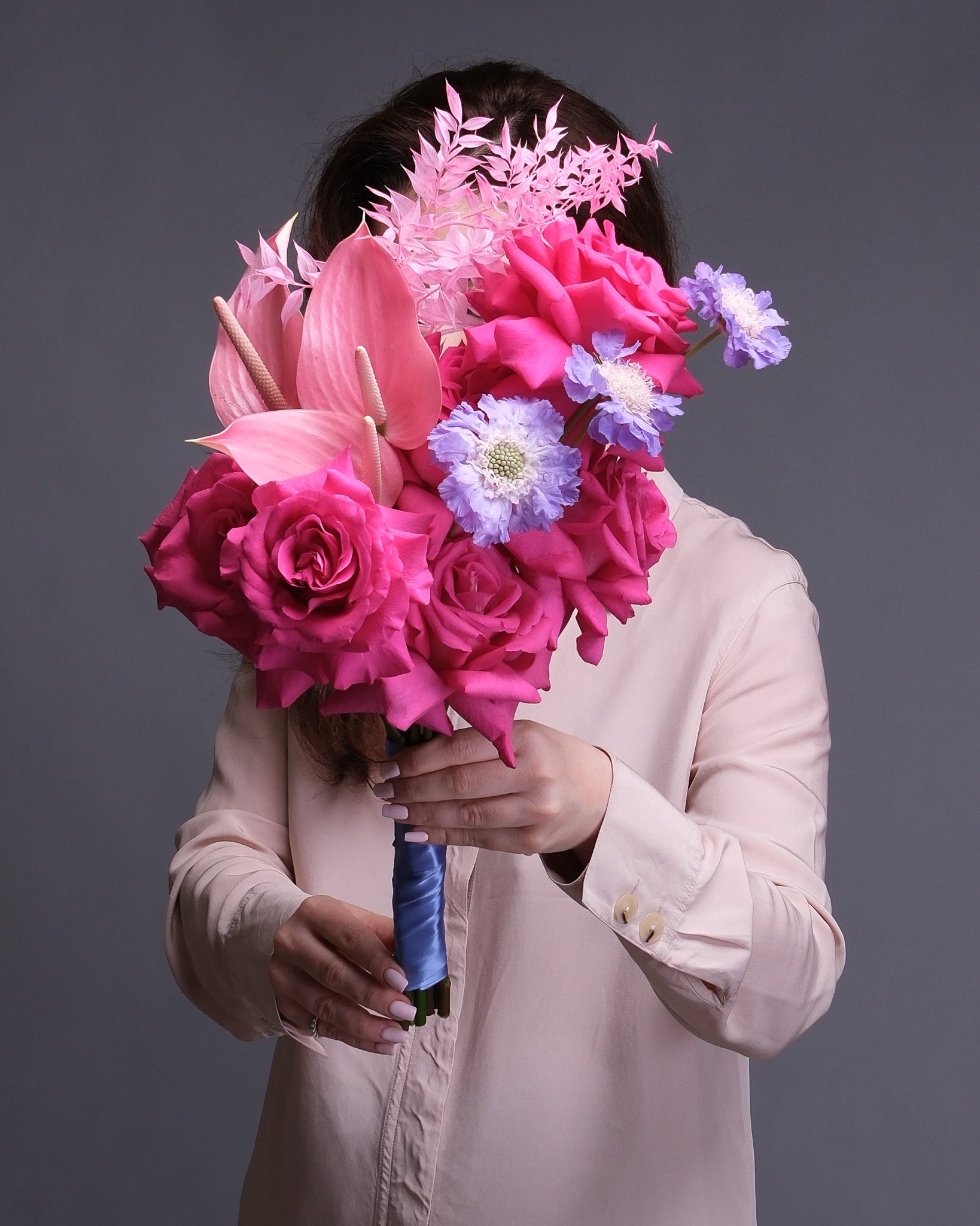 Person holding a bouquet of pink bridal bouquet against a dark background