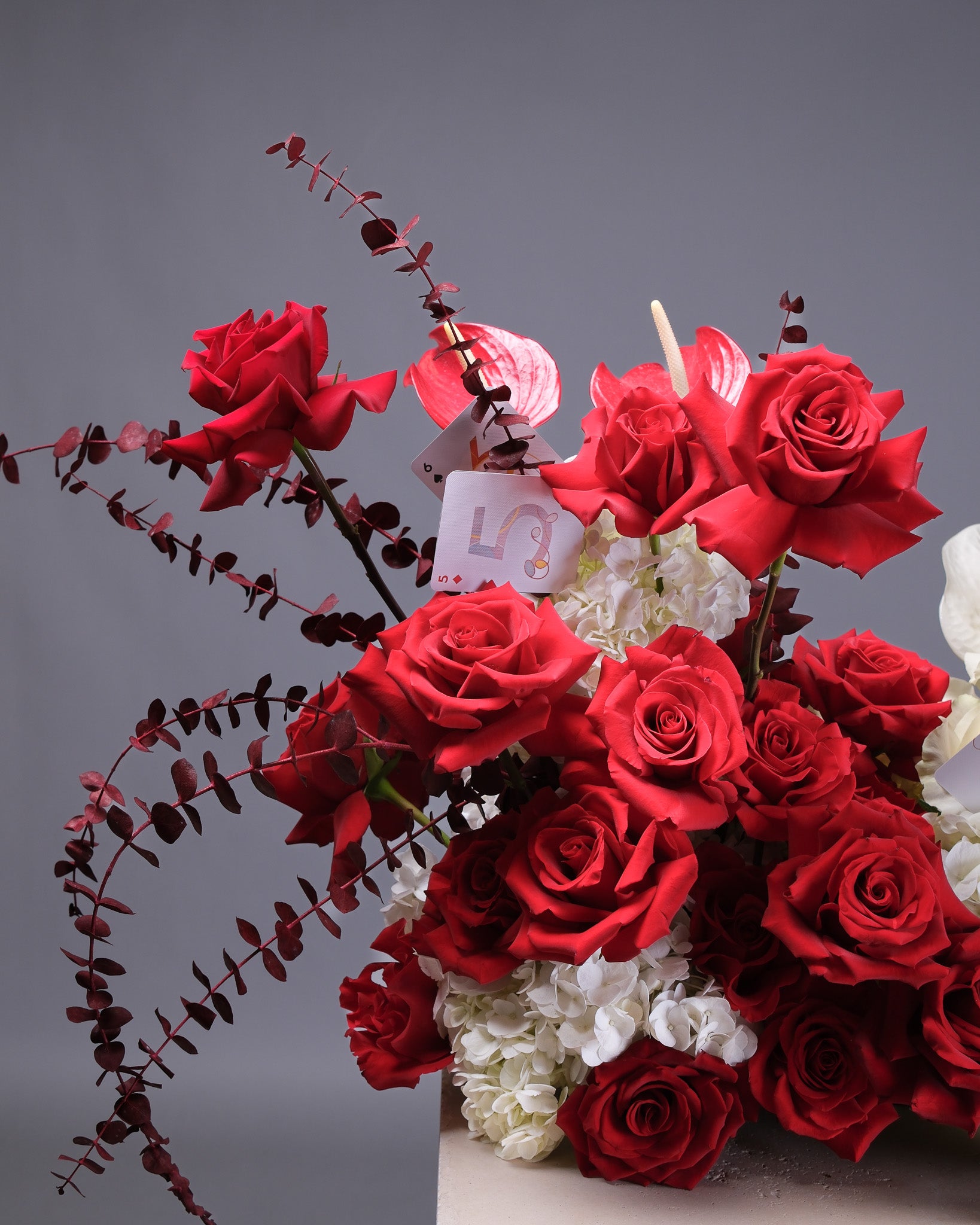 Bouquet of red roses with a small white angel figurine on a gray background