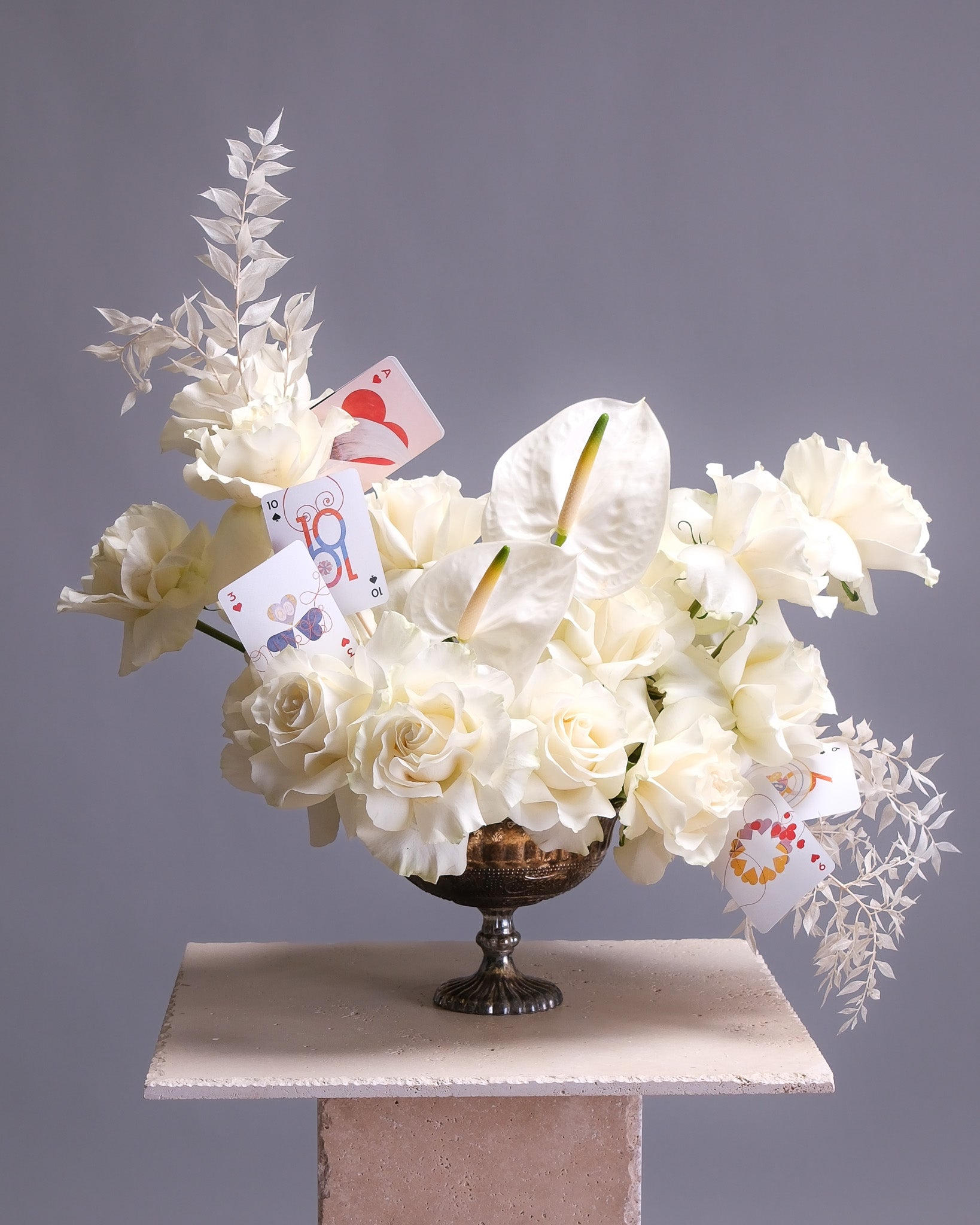Floral arrangement with playing cards on a gray background