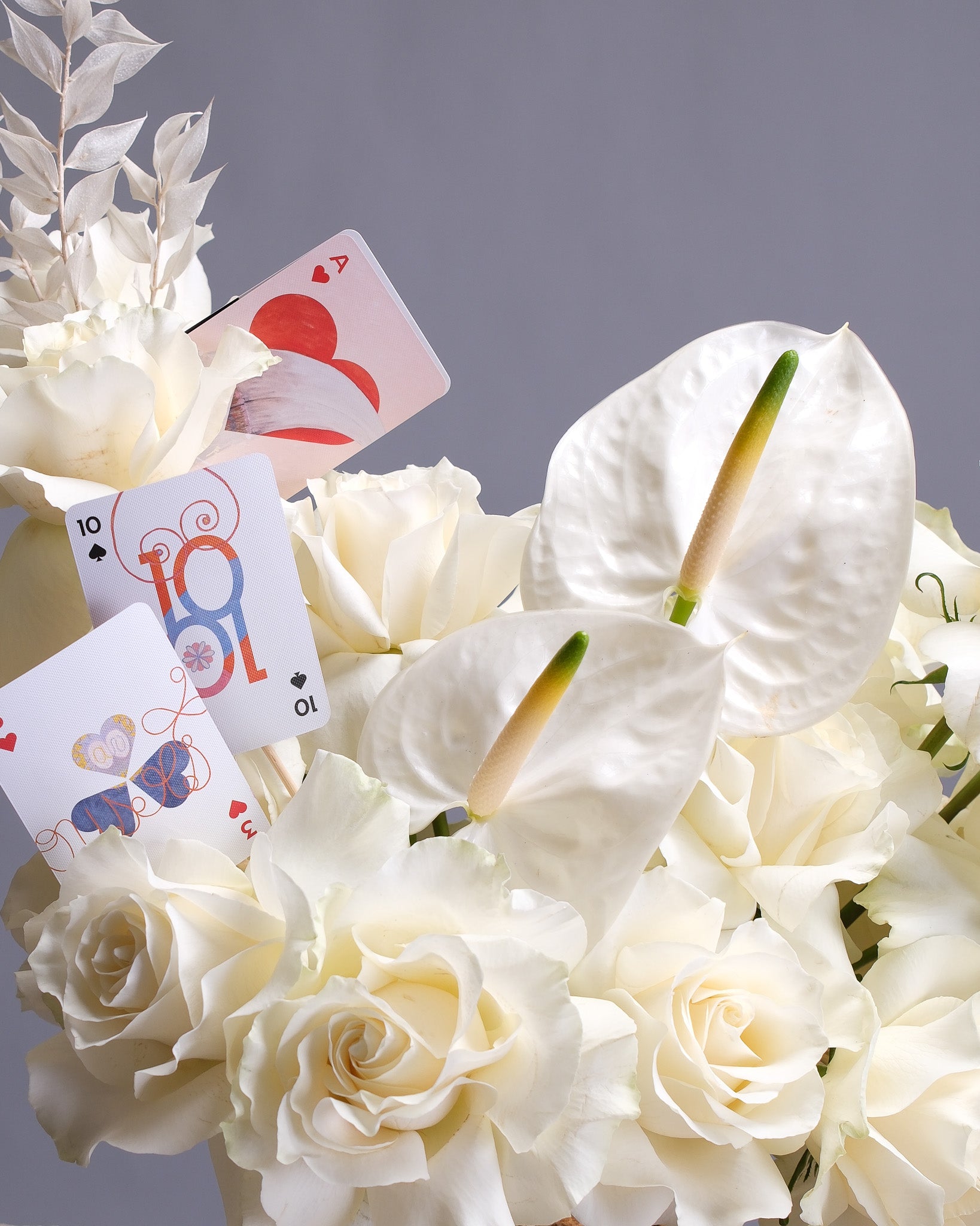 Bouquet of white flowers with playing cards on a gray background